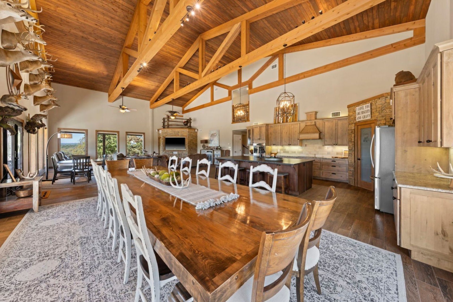 Just off the kitchen, the dining area features a long, solid wood table surrounded by a mix of white ladder-back and natural wood chairs.