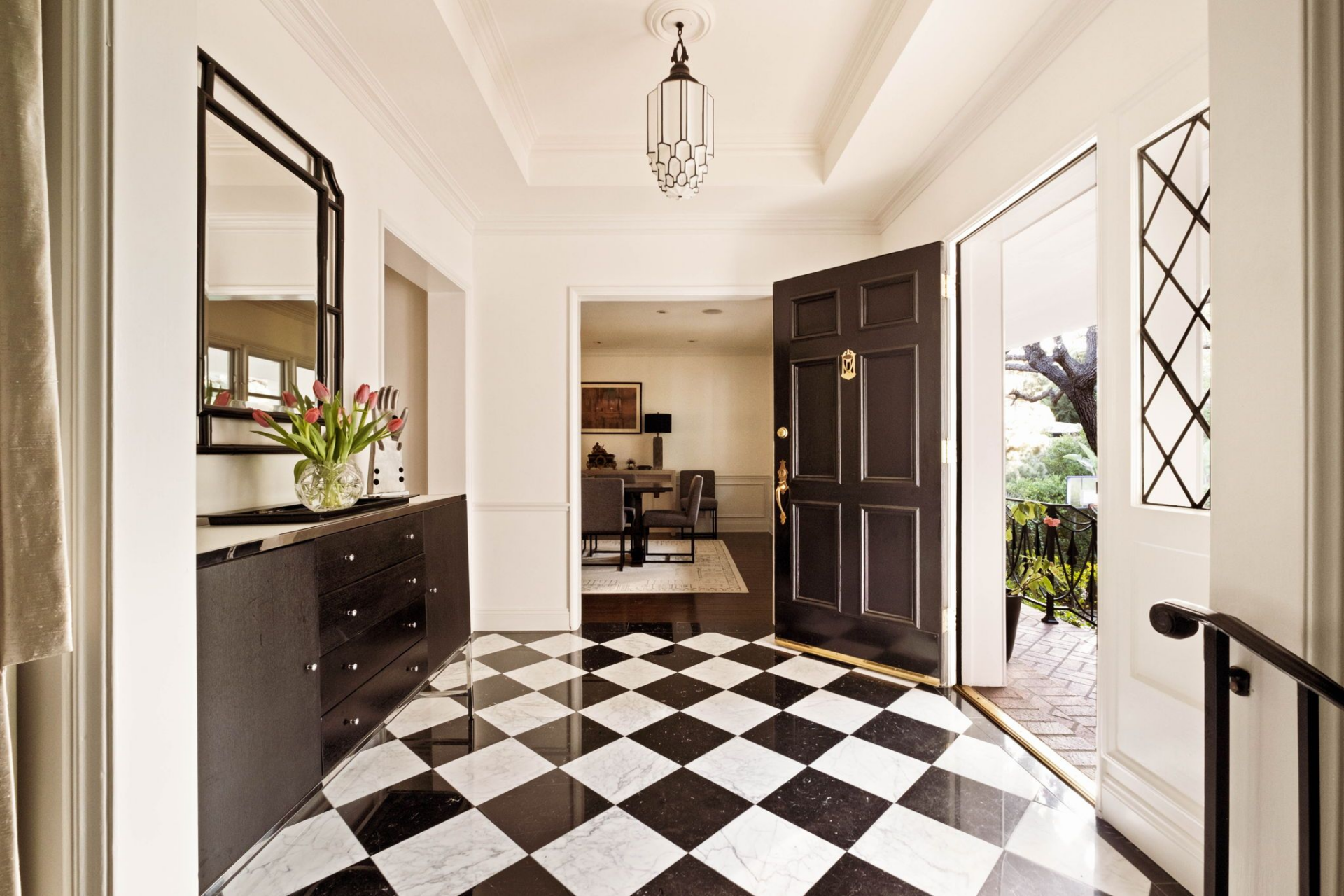 Inside, the home opens to a striking black-and-white marble foyer arranged in a classic checkerboard pattern. 