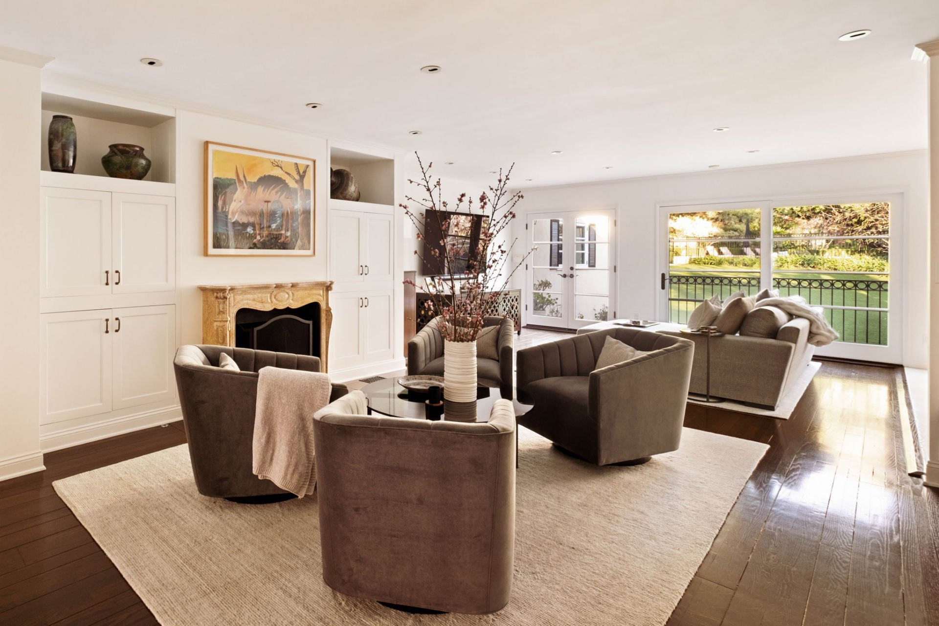 The family room is centered around a carved wood-burning fireplace set into a traditional mantel, its warm stone surround framed by custom white built-ins. 