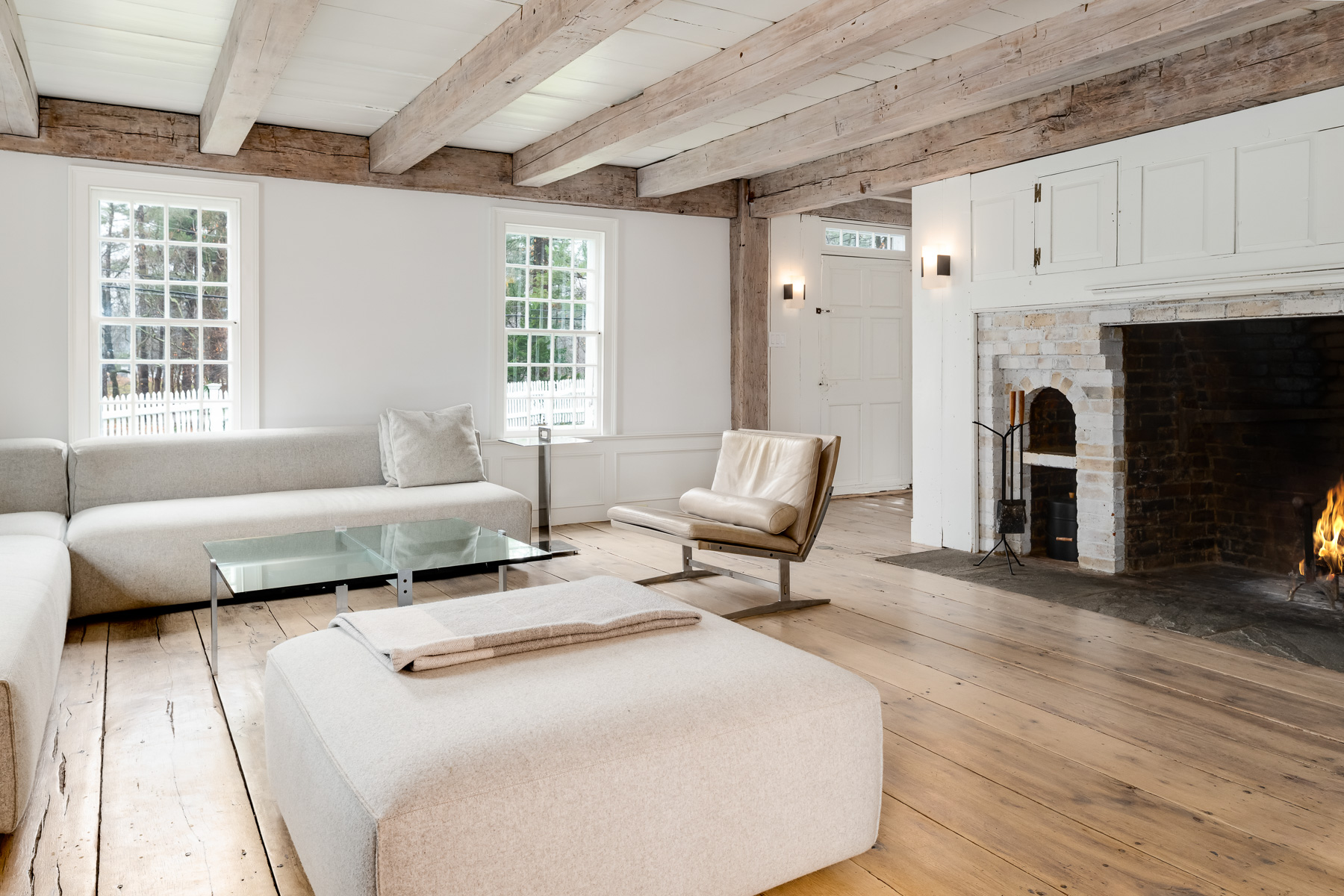 Wide-plank antique floors that stretch across the room, their natural grain and patina setting a grounded tone beneath exposed, hand-hewn wood beams that run overhead.