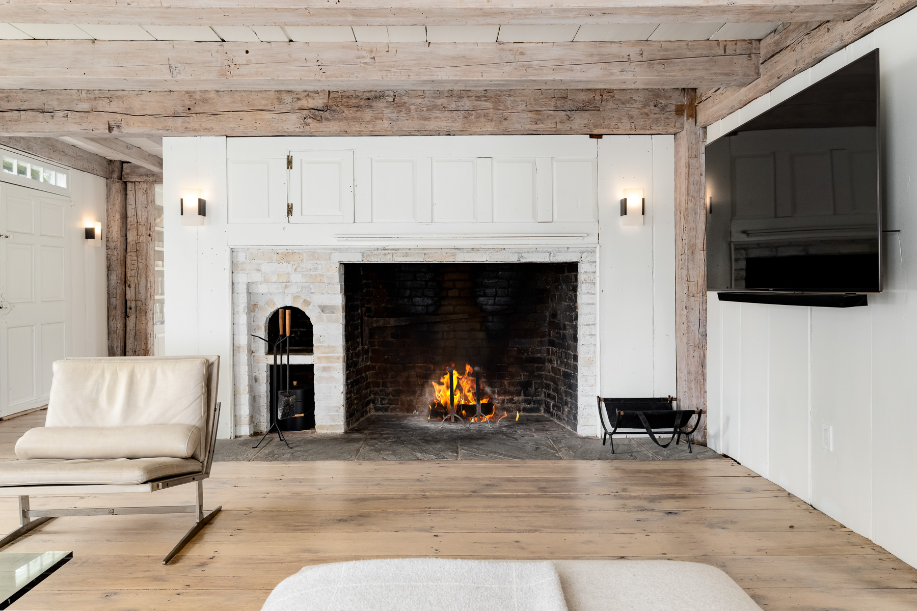 Straight ahead, the first of several preserved fireplaces anchors the wall in painted brick, its firebox deep and original, framed by simple millwork. 