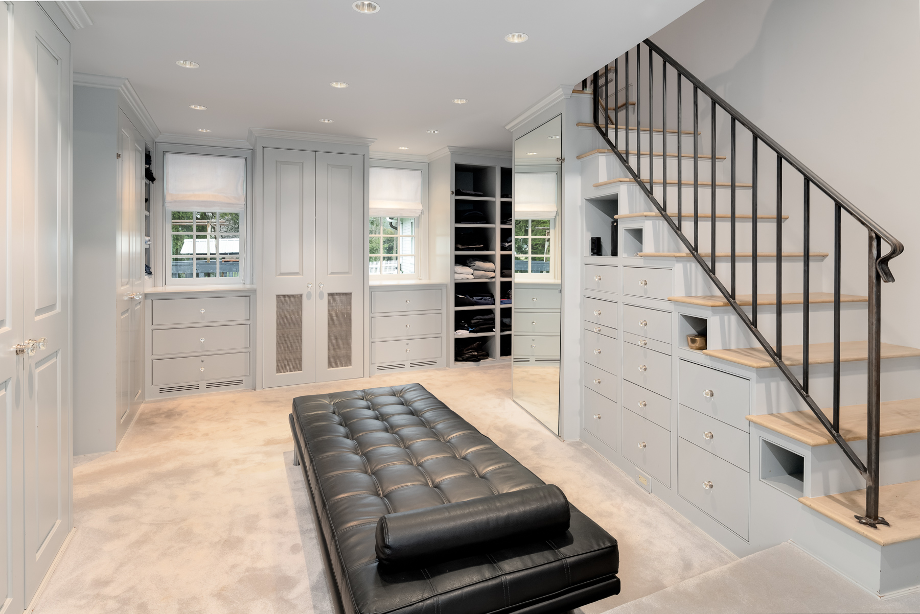 Connected to the bedroom is a custom dressing room designed with both function and scale in mind. Built-in cabinetry lines the walls, offering a mix of drawers, concealed storage, and open shelving. 