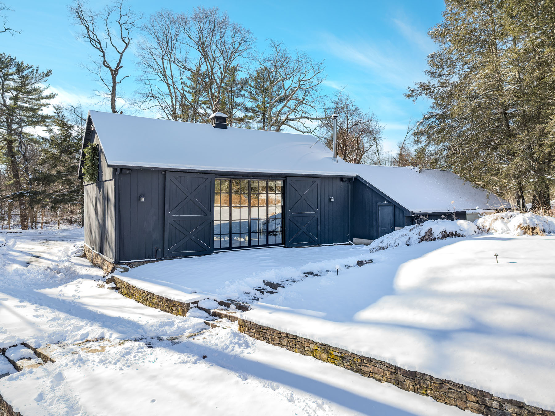 From the outside, its dark wood siding and sliding barn doors nod to the property’s agrarian roots, while oversized glass doors open the space up to the surrounding landscape, creating an indoor-outdoor flow even in the colder months.