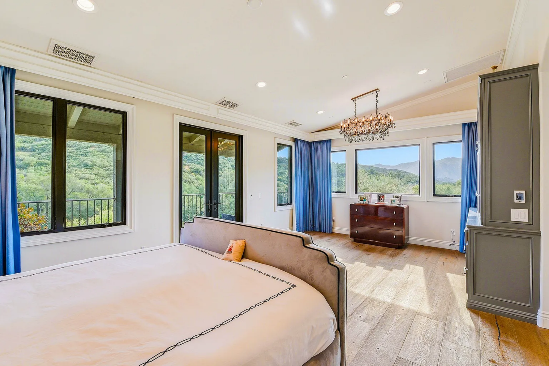 Floor-to-ceiling windows and French doors draw in natural light, while wide plank wood floors and soft neutral tones keep the space calm and open.