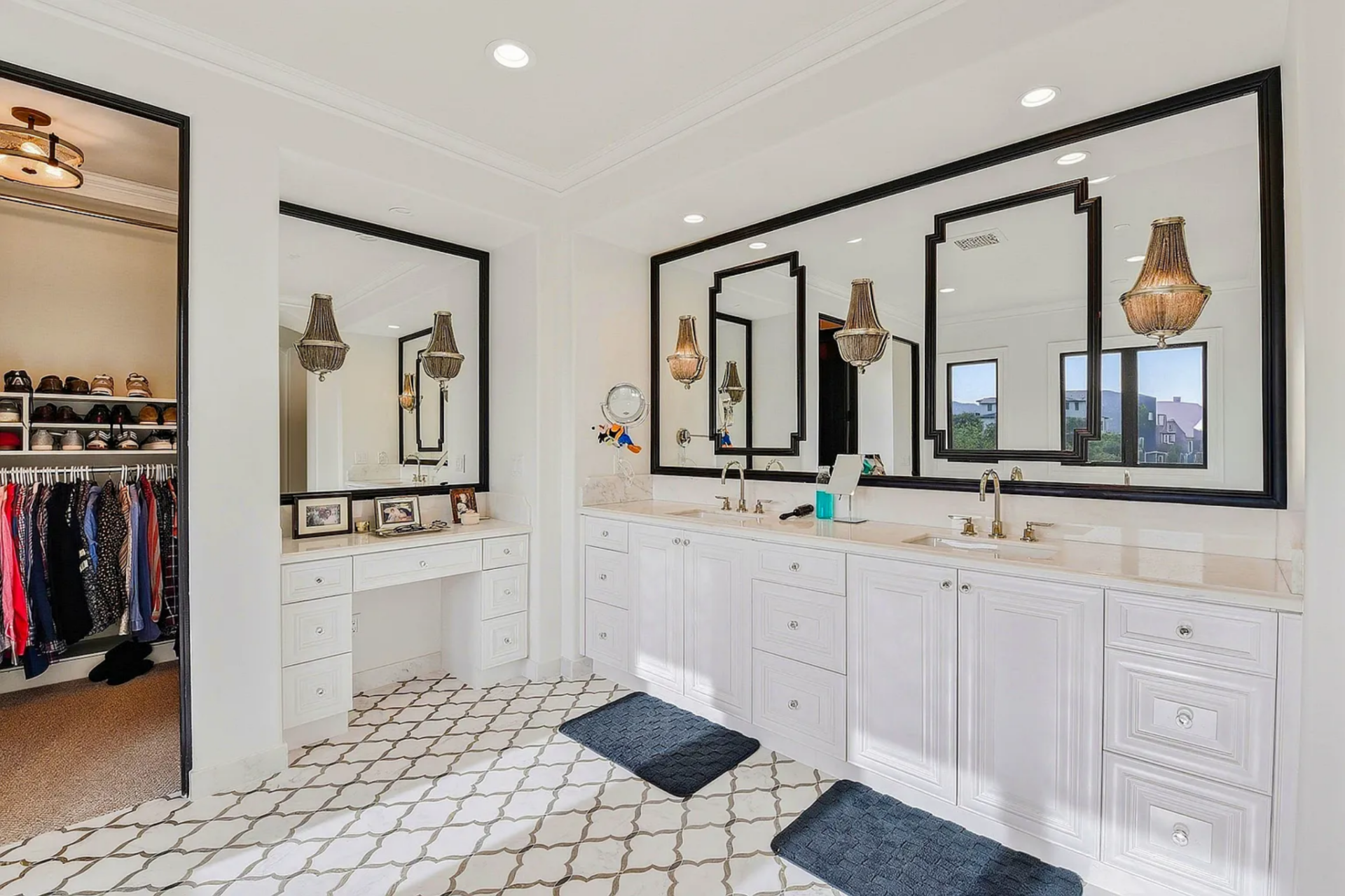 Dual vanities with oversized framed mirrors and detailed cabinetry are next to the walk in closet.