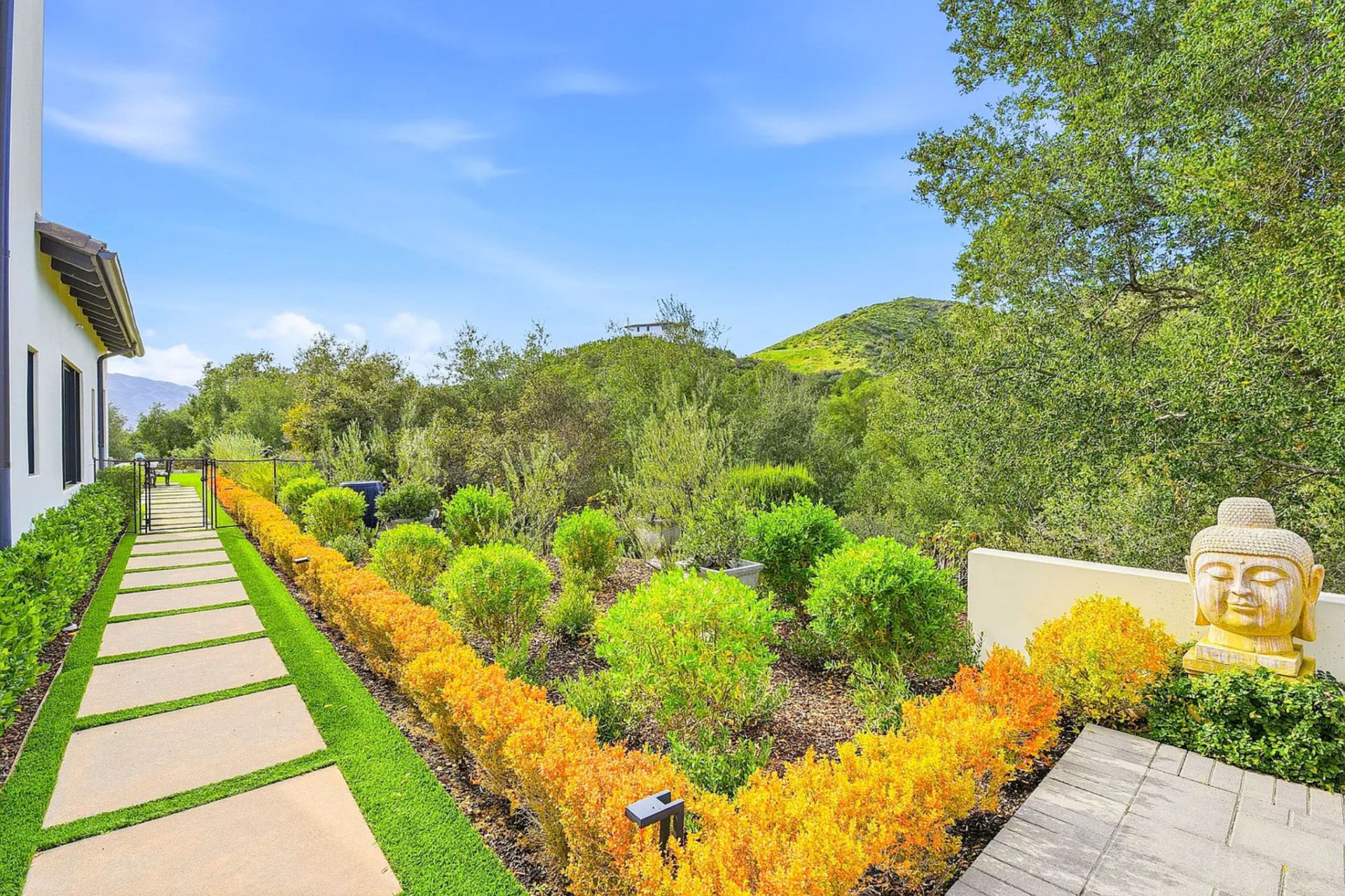 Along the perimeter, peaceful Zen gardens create moments of stillness along the walking paths, made up of structured hedges, layered plants, and a sculptural Buddha.