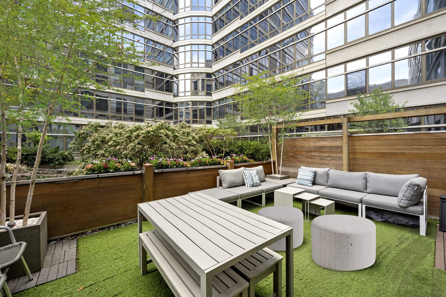Extending directly off the second-floor living room, the private terrace opens as a contained outdoor room framed by wood privacy panels and raised planters filled with greenery. 