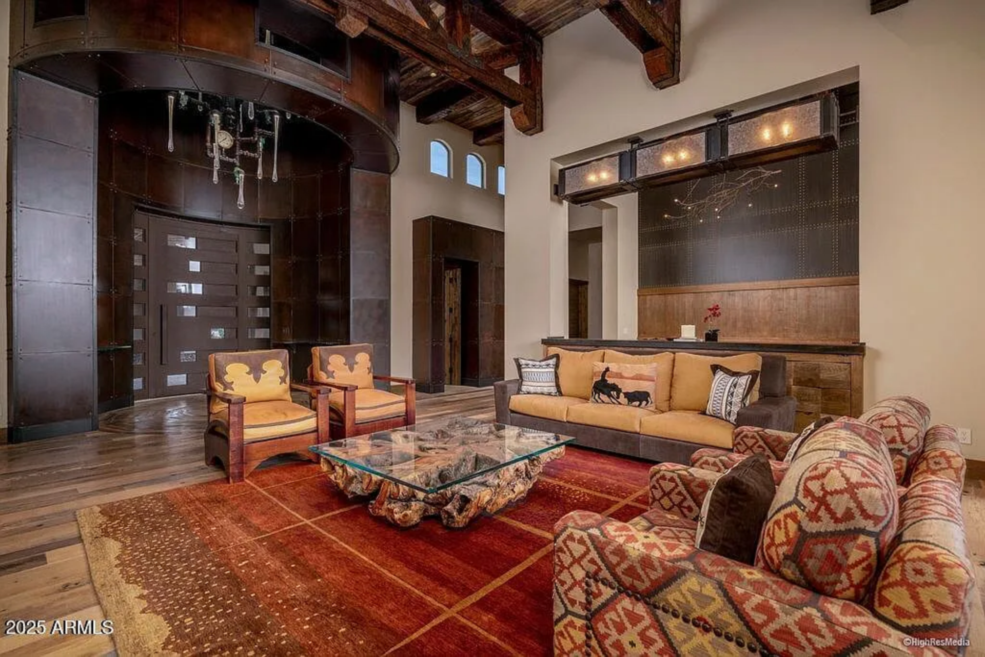 The seating area feels both refined and grounded, arranged around a glass-topped coffee table set on a richly patterned rug.