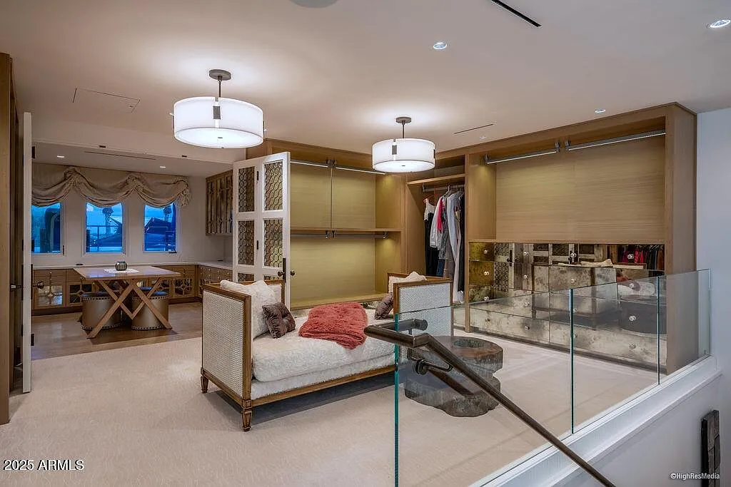 A staircase leads to an upstairs level, creating additional storage and display space, making the closet feel more like a private fashion atelier than a traditional wardrobe room.