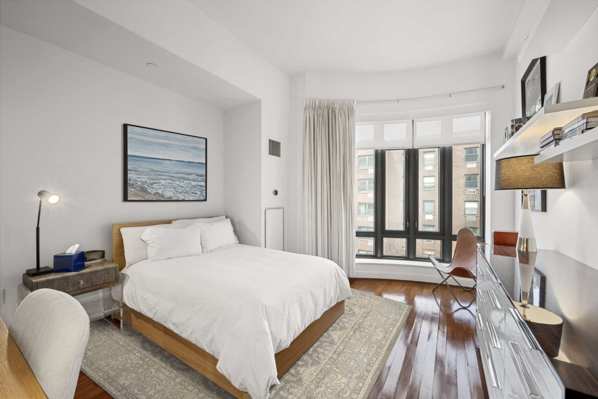 This room is defined by integrated shelving and a streamlined storage wall that runs opposite the bed, offering both display and practical storage. 