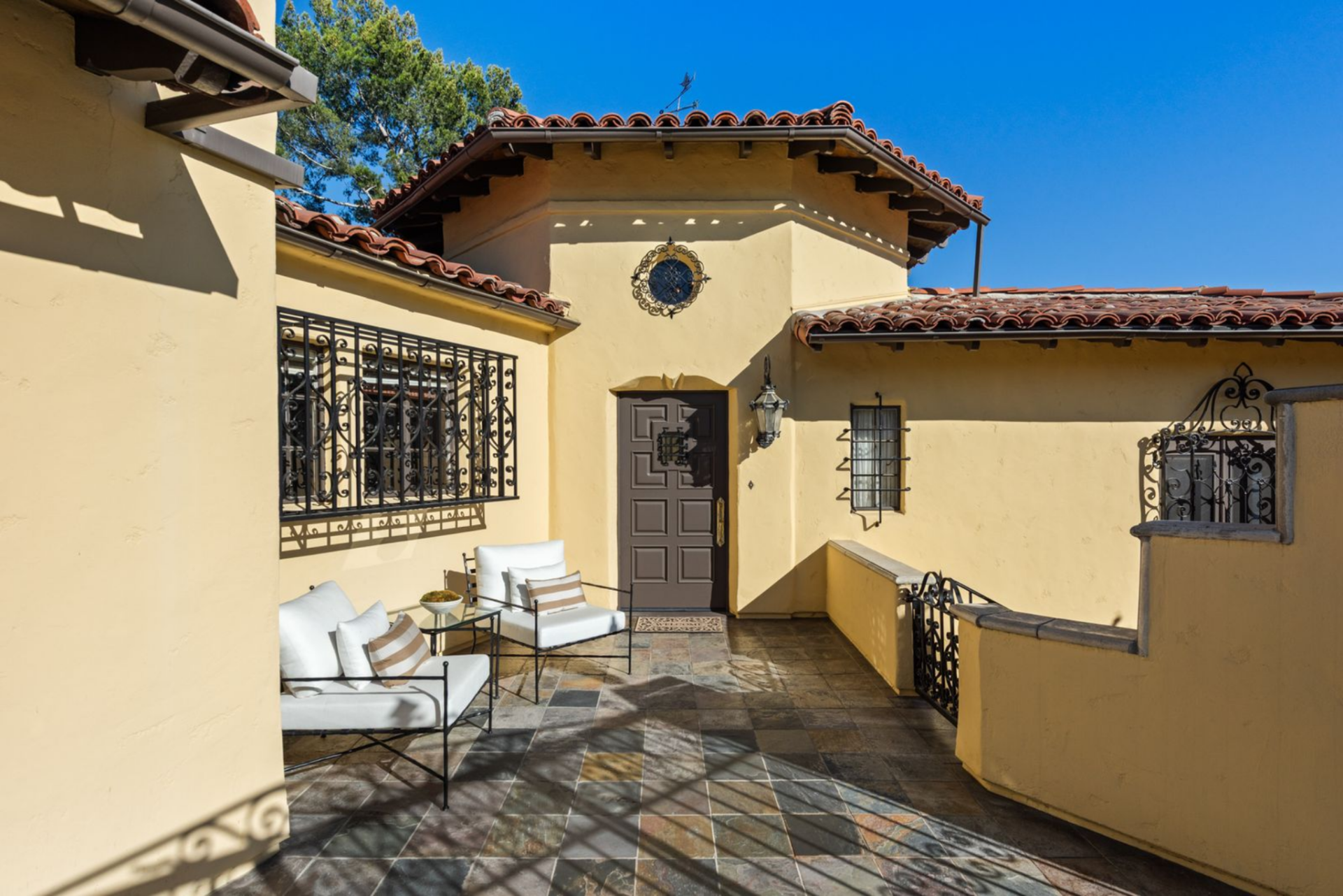 As you pass the gate and step onto the tiled entry terrace, you'll see that iron grilles guard the windows surrounding a carved wooden door that sits within a modest tower.