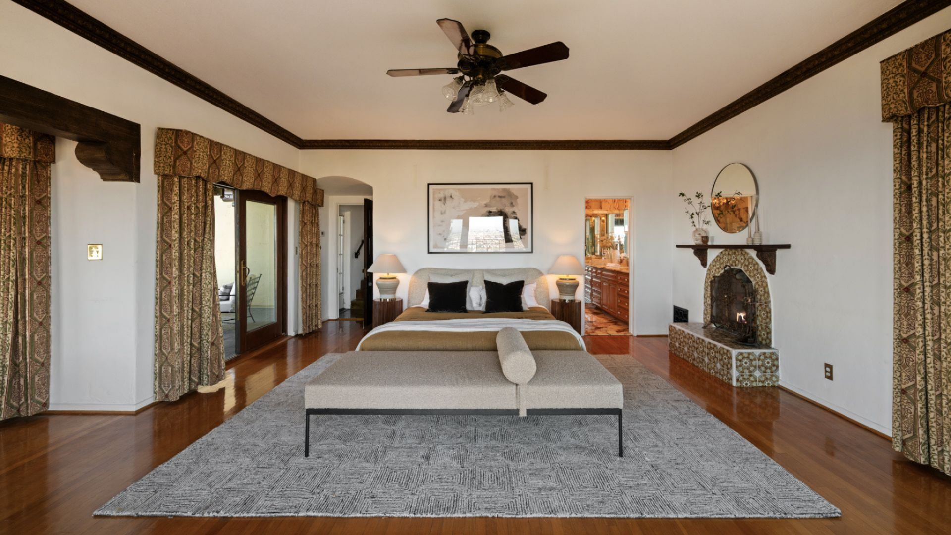 The home's primary suite occupies a broad space, arranged symmetrically with the bed centered against the main wall and framed by matching nightstands and lamps.
