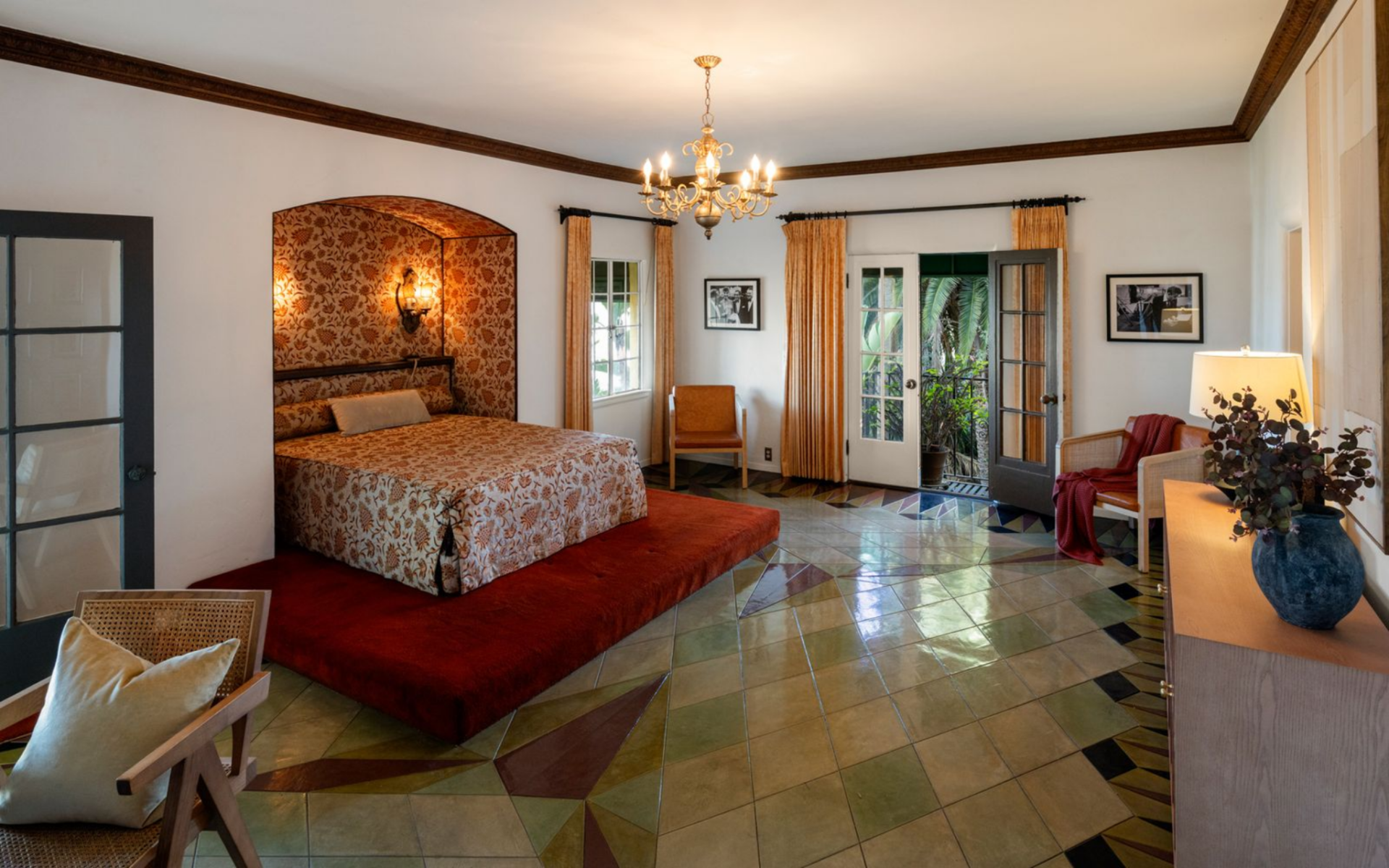 This room is organized around a recessed sleeping niche wrapped in bold, patterned fabric that extends across the walls and upholstered headboard.