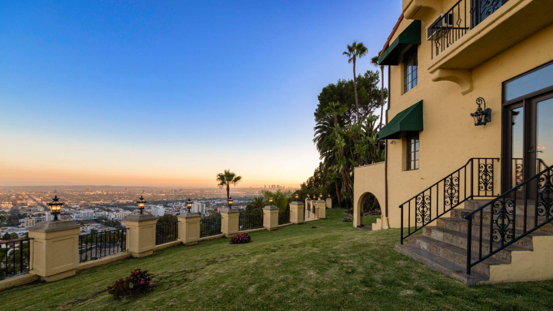The full-height glass doors from the ballroom open directly to the backyard, where a stretch of lawn meets a balustrade overlooking the Los Angeles skyline.