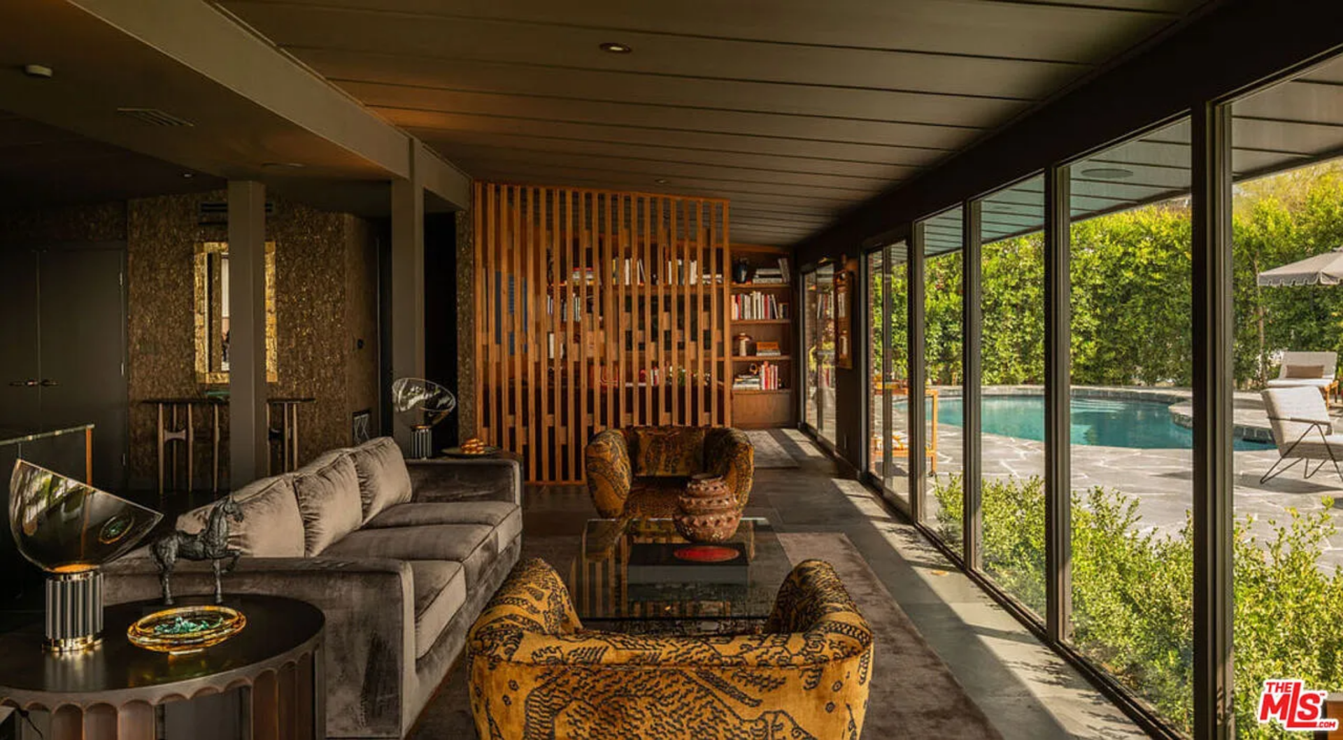 A low, square coffee table grounds the seating arrangement, while accent chairs introduce contrast through bold fabric and curved silhouettes.