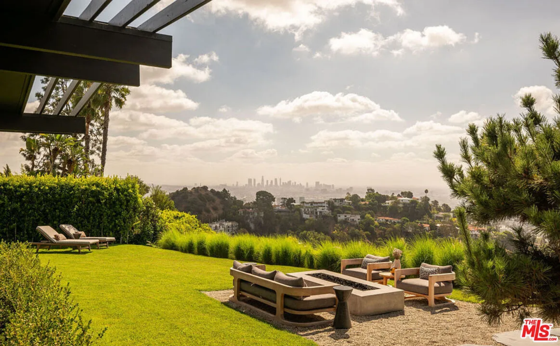 At its center, a sunken fire feature is framed by low-profile seating, arranged to face outward toward the panoramic city views rather than inward toward the house.