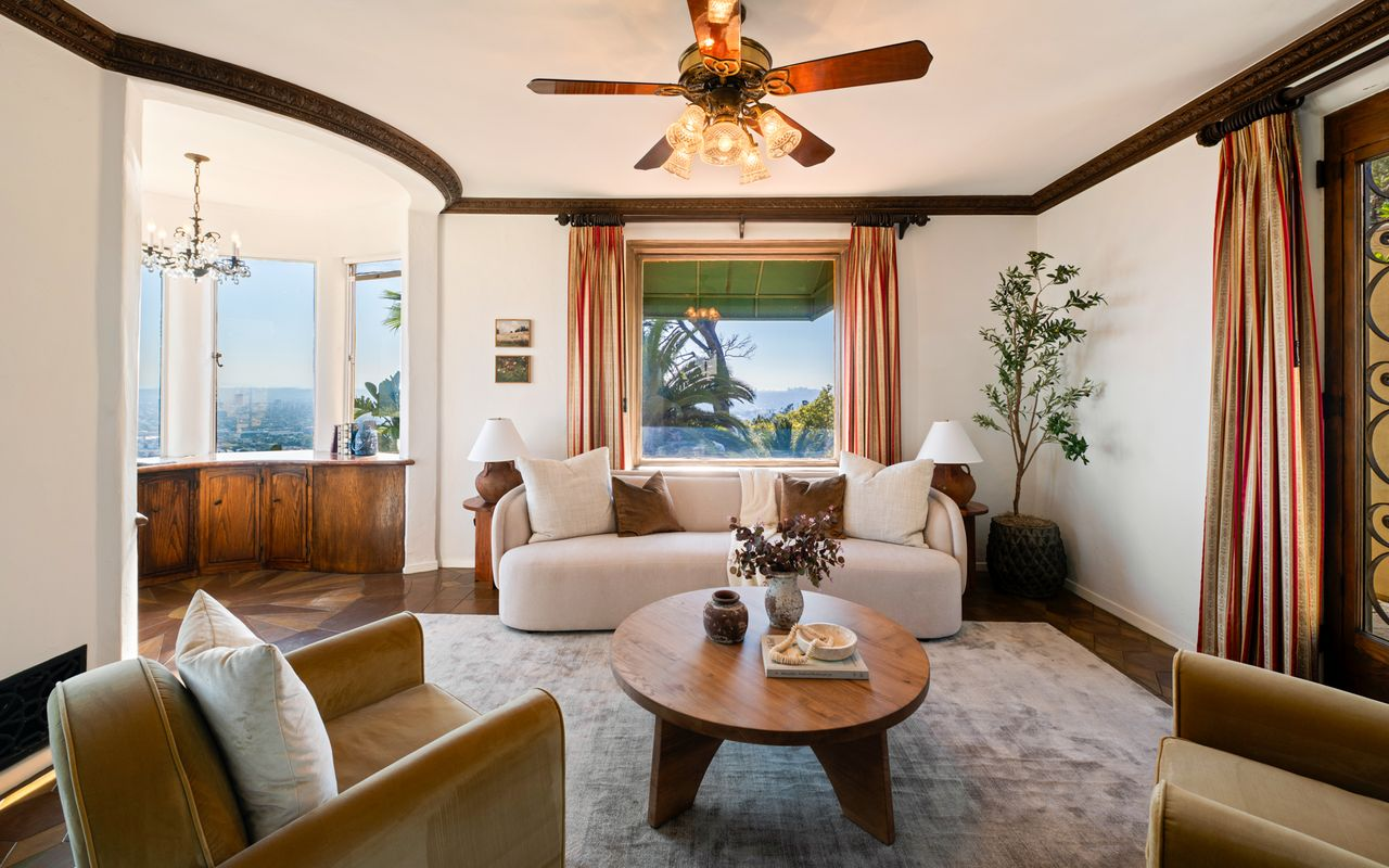 Original wood trim frames the space, while striped drapery and wrought-iron details echo the Spanish Revival architecture seen outside.