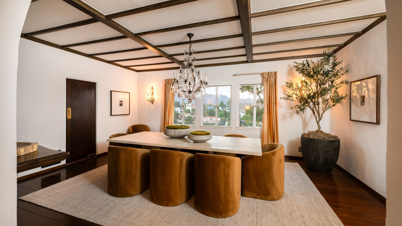A long, rectangular dining table runs down the center, surrounded by upholstered barrel chairs that soften the room’s architectural lines.