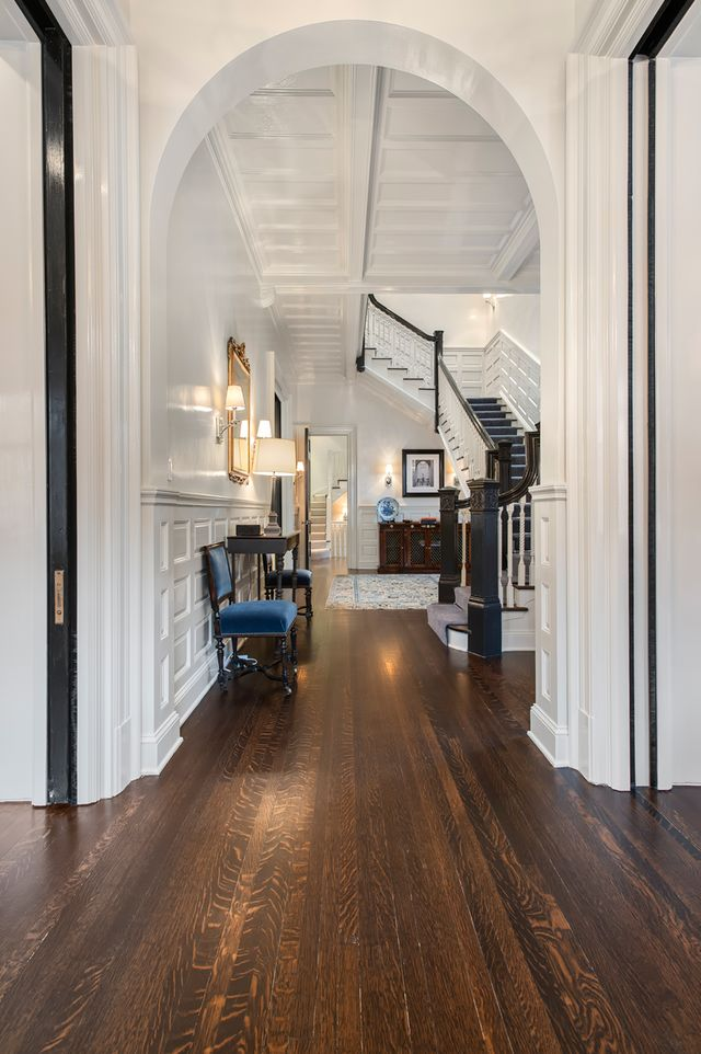 Inside, the striking entry hall features original paneling that lines the walls beneath a coffered ceiling, while dark-stained hardwood floors run toward the main staircase. 