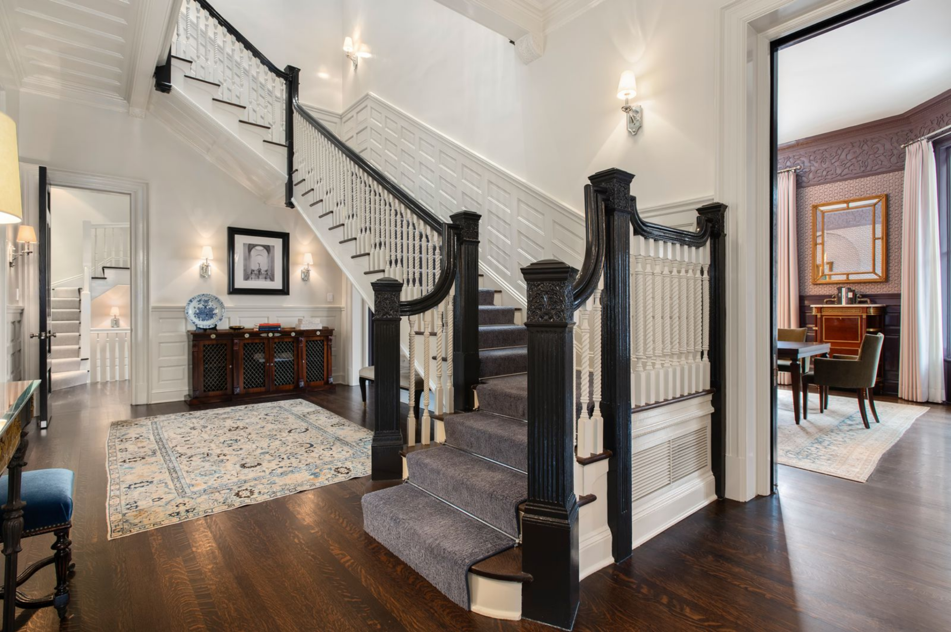 At the center of the foyer, is a grand staircase, its carved posts finished in a deep contrasting stain against crisp white balusters. 