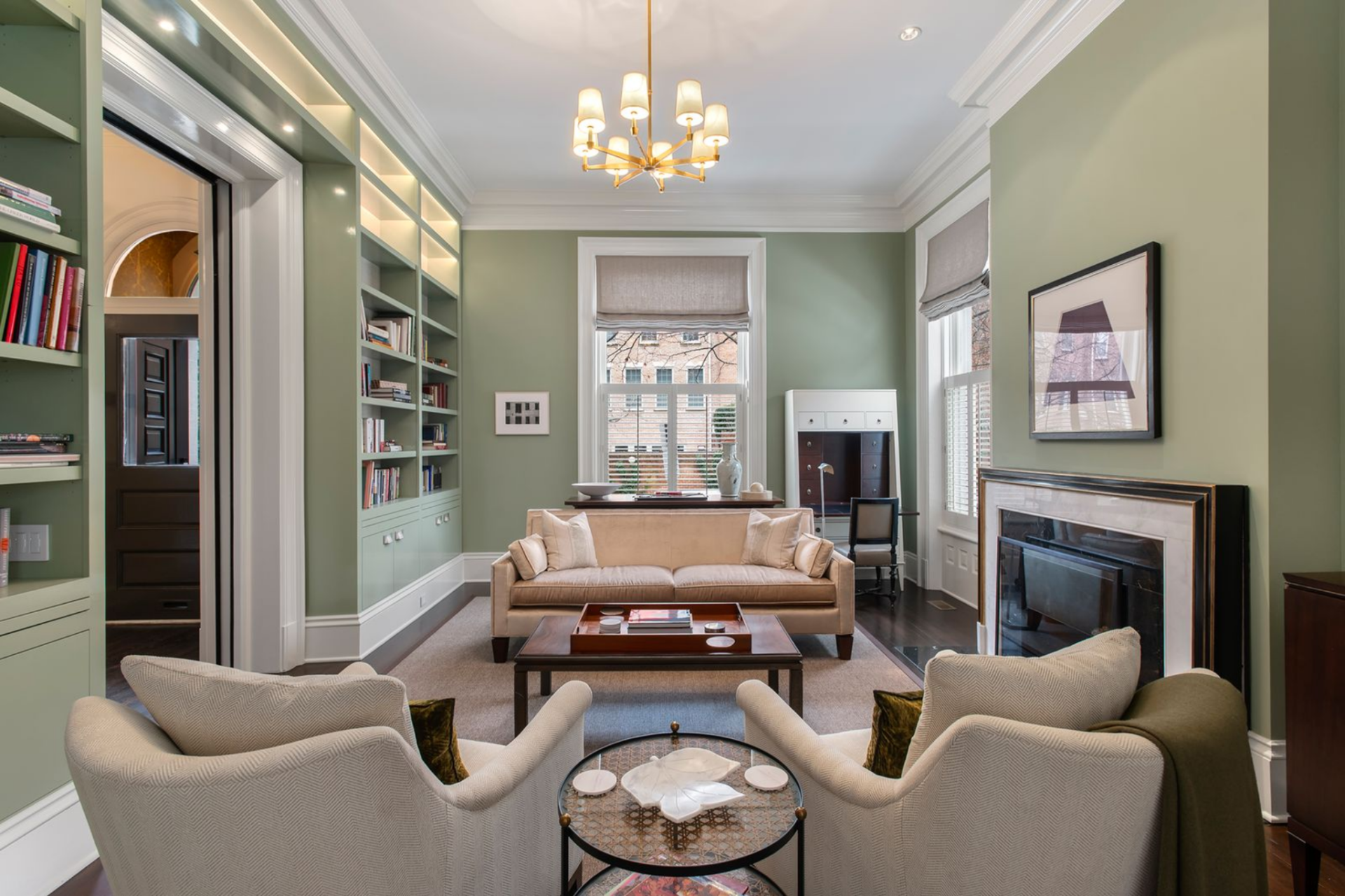 A tailored sofa sits opposite a pair of armchairs, arranged around a rectangular wood coffee table atop a neutral area rug, reinforcing the room’s balanced proportions.