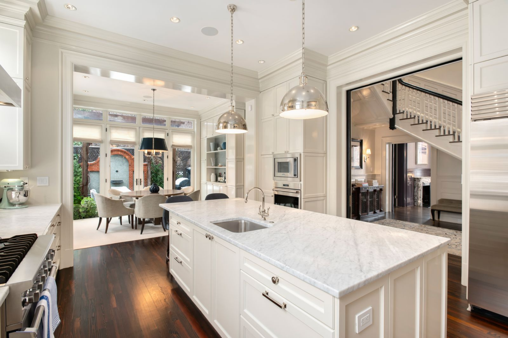 A professional-grade range sits between twin windows, complemented by Sub-Zero refrigeration, Viking cooking appliances, and Bosch built-ins integrated along the perimeter.