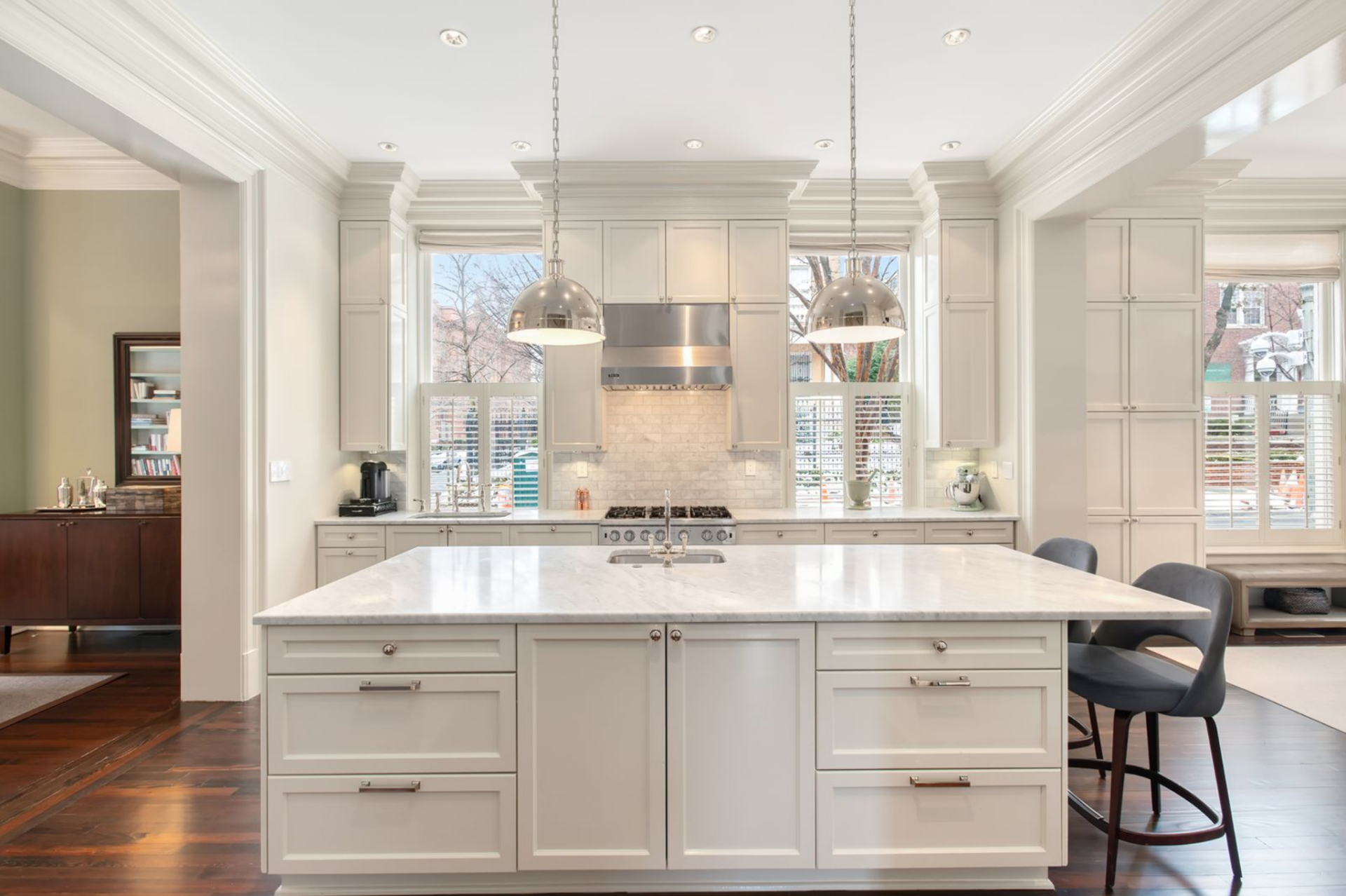 A professional-grade range sits between twin windows, complemented by Sub-Zero refrigeration, Viking cooking appliances, and Bosch built-ins integrated along the perimeter.