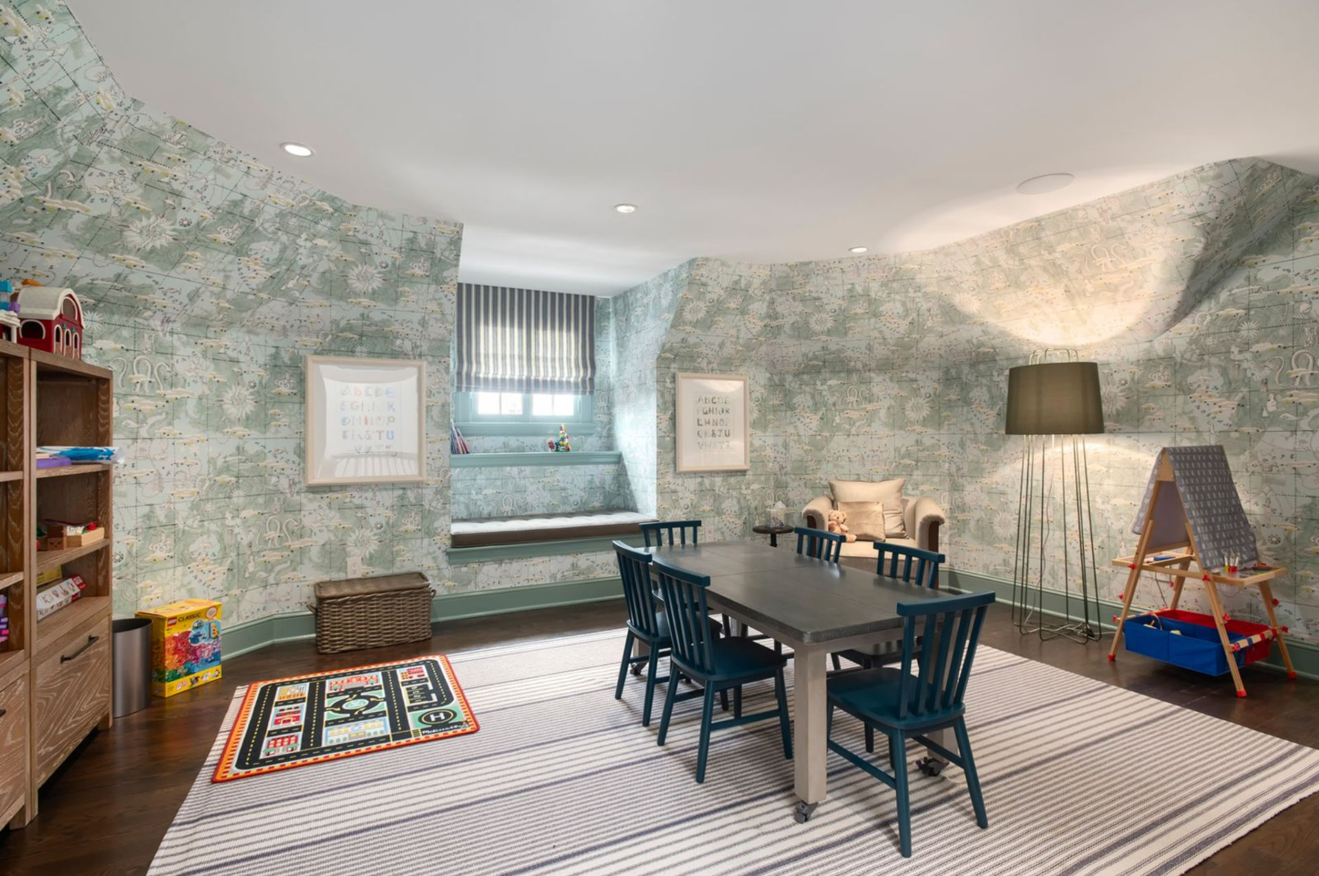 On the upper level, the kids’ playroom is carved into the roofline, with softly angled walls wrapped in a whimsical, map-inspired wallpaper. 