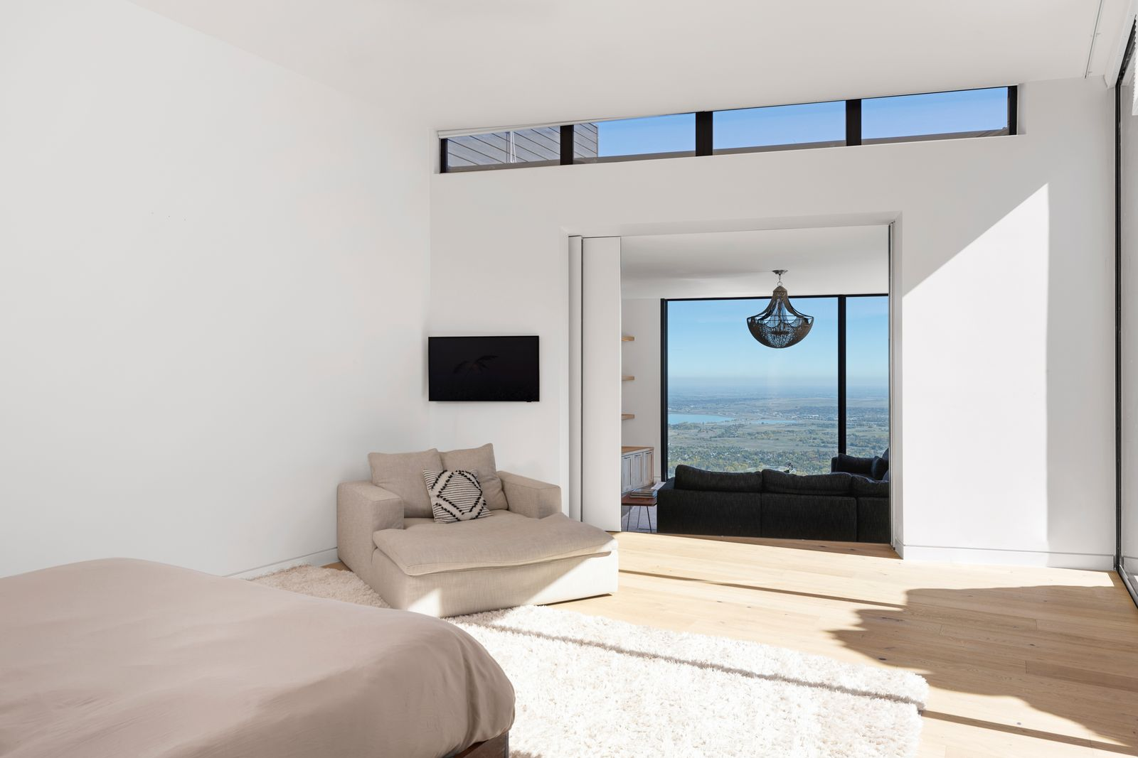 Soft textiles, sculptural lighting, and carefully layered neutrals keep the room feeling grounded, while natural light filters in to highlight the clean lines and generous size.