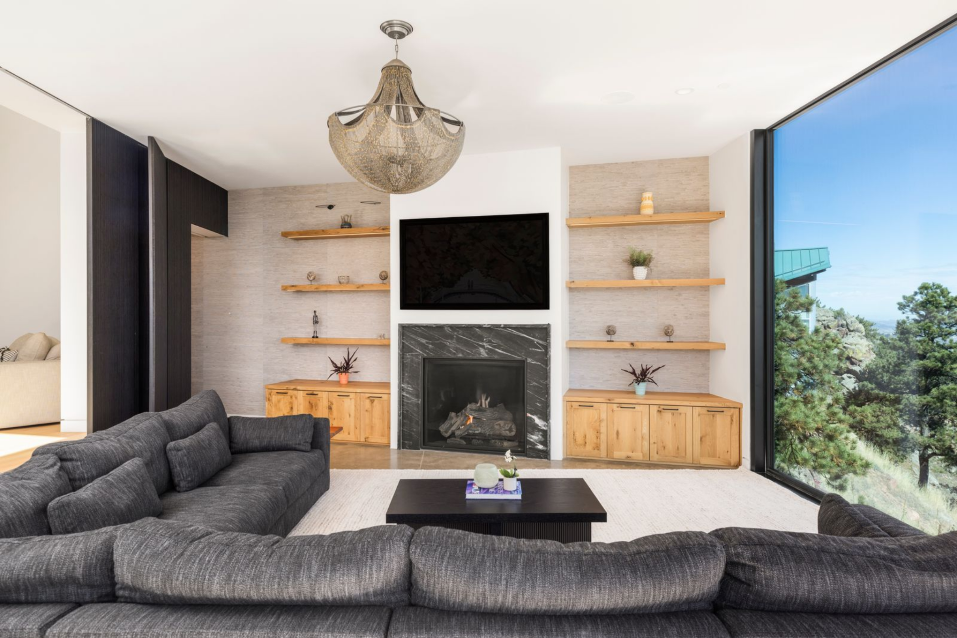 Private media room designed as an intimate lounge, where a deep sectional faces a marble-wrapped fireplace and wall-mounted TV framed by built-in shelving. 