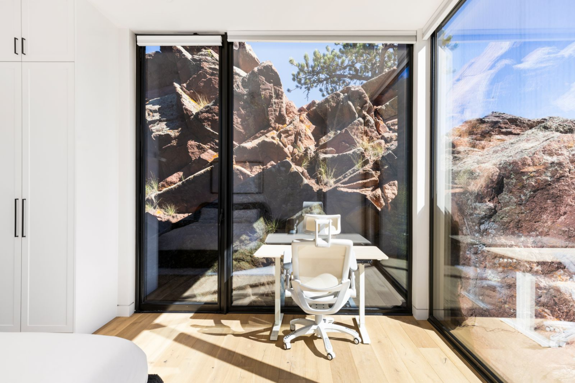 A desk positioned in front of full wall of glass with a view of unique red rock formation.