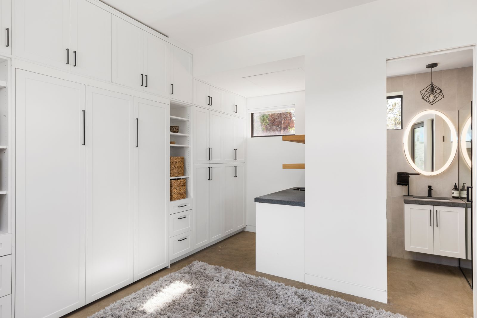 Built-in cabinetry lines one wall, providing storage and making the room feel polished, while a compact wet bar adds convenience for longer stays or creative use. 