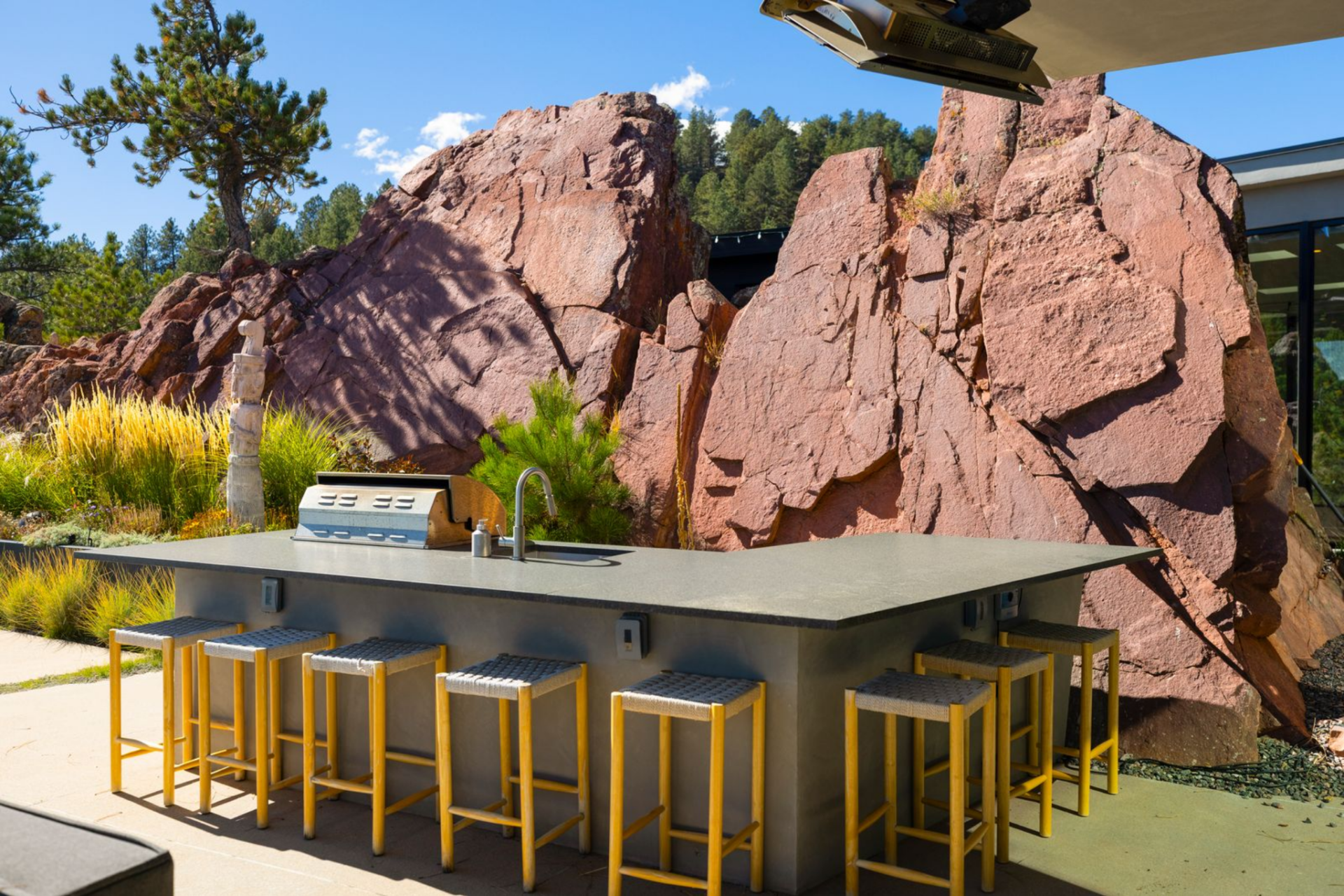 A built-in grill and full outdoor kitchen are paired with an oversized bar, offering seating for dining and entertaining. 