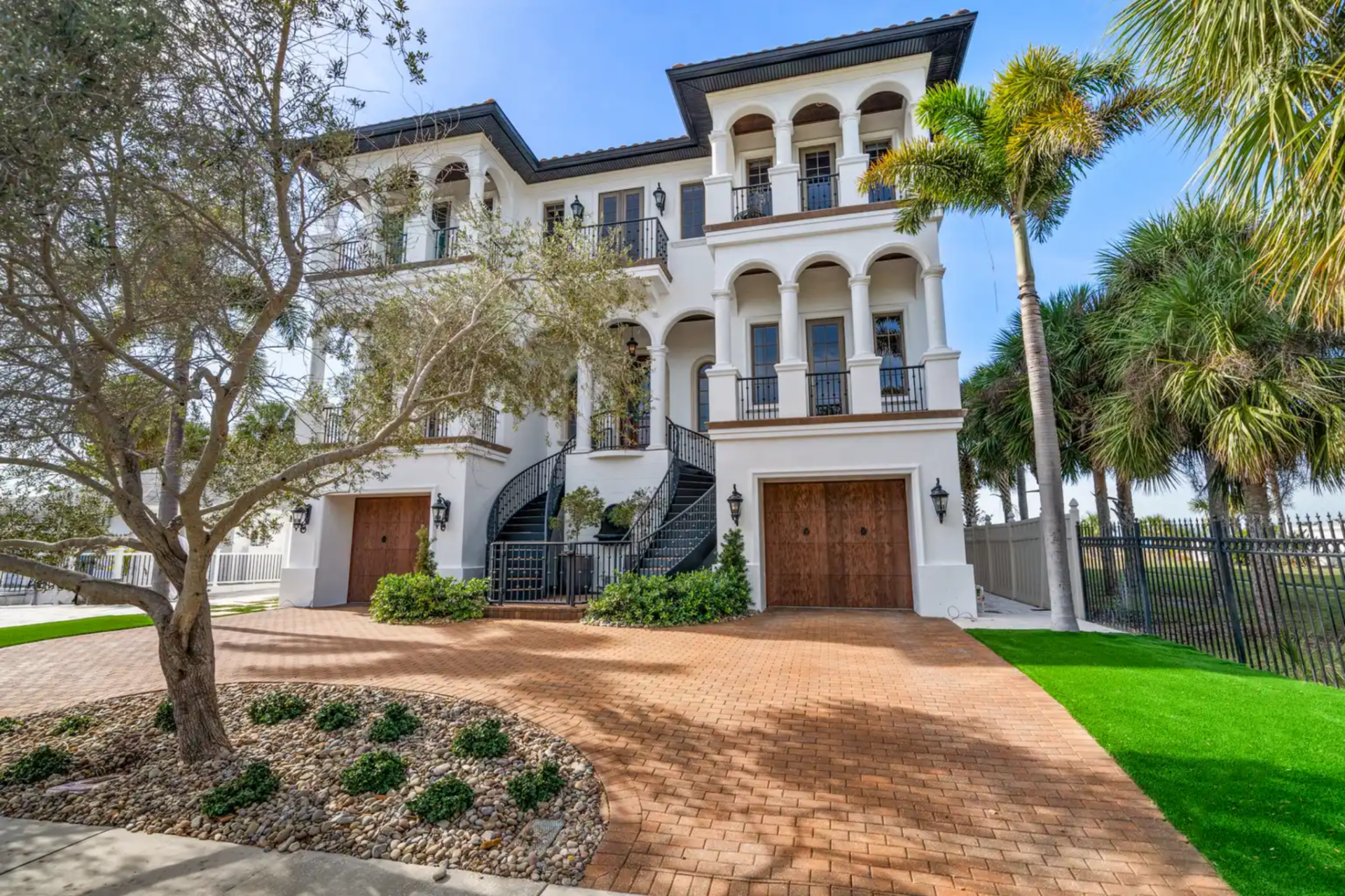 As you walk up to Hogan's Florida home, the scale immediately strikes you with white stucco walls, arched balconies, and palm trees framing the wide brick driveway that leads to the front entry.