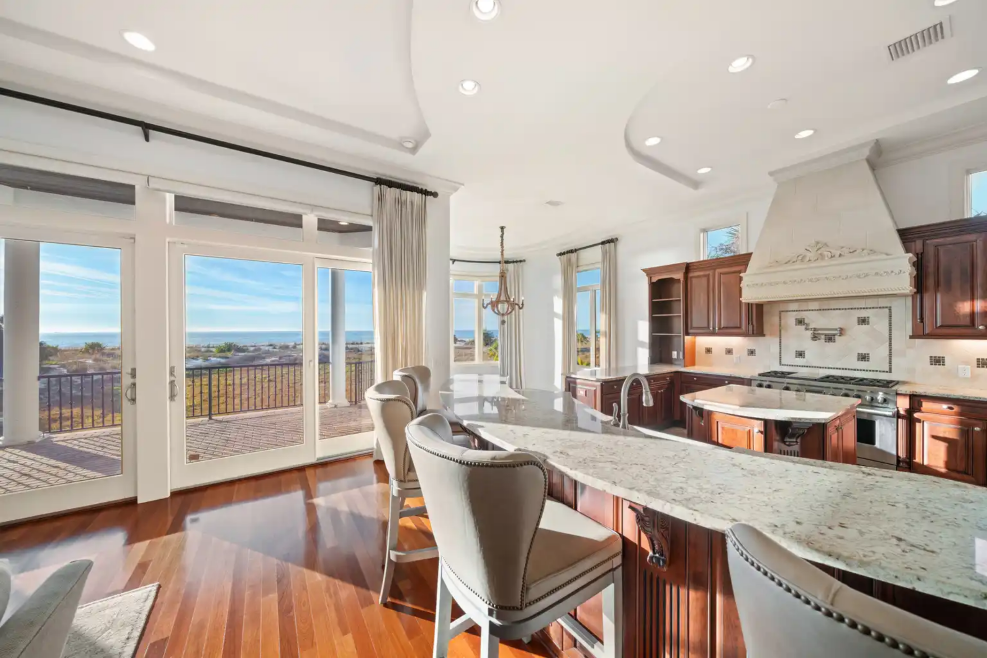 Just behind the living room, the designer kitchen unfolds as a generous, open space defined by rich wood cabinetry, expansive marble countertops, and multiple islands.