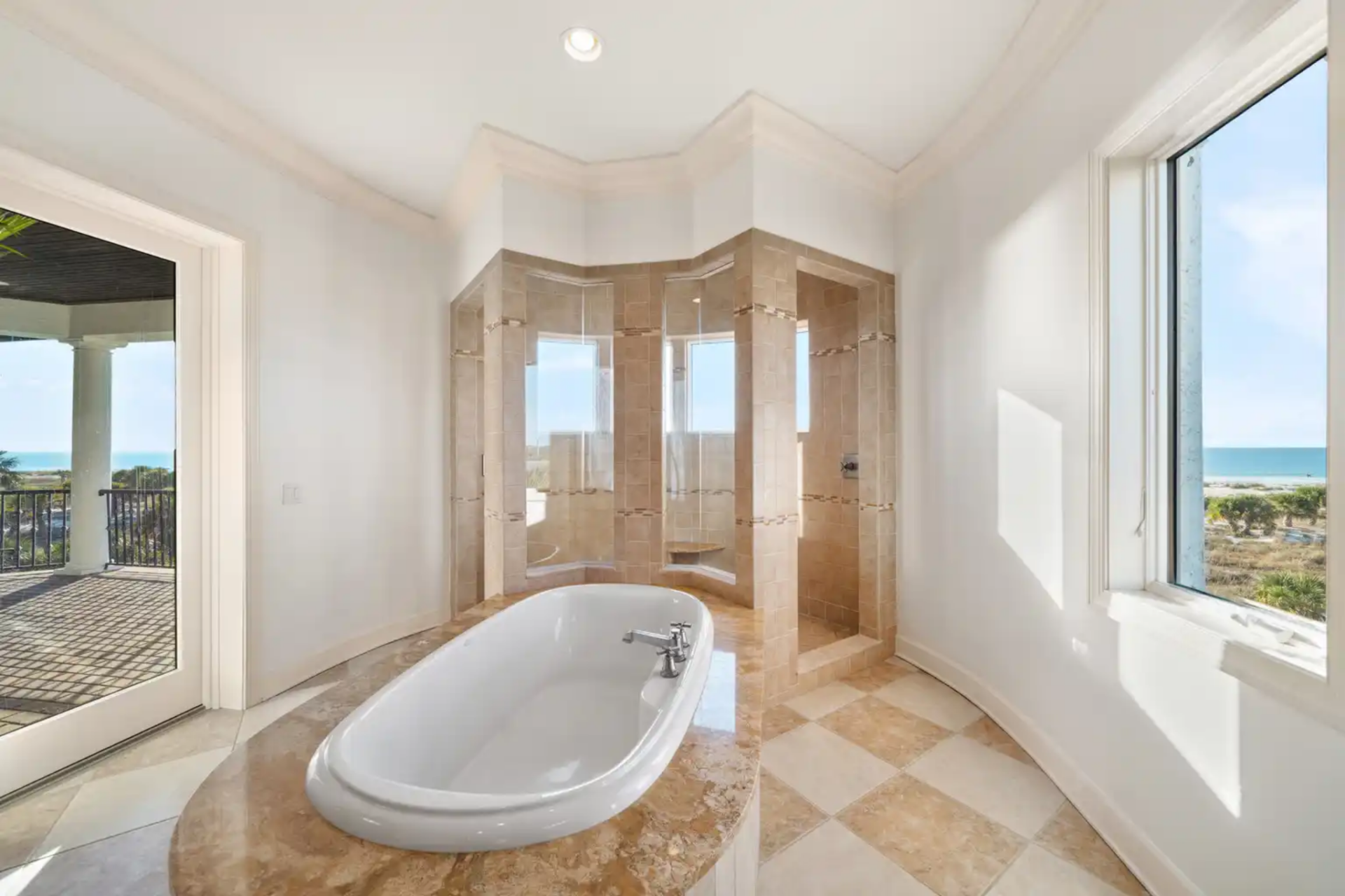 Following the vanity's line of sight, the checkered flooring leads to a soaking tub and glass-enclosed shower set between tall windows.