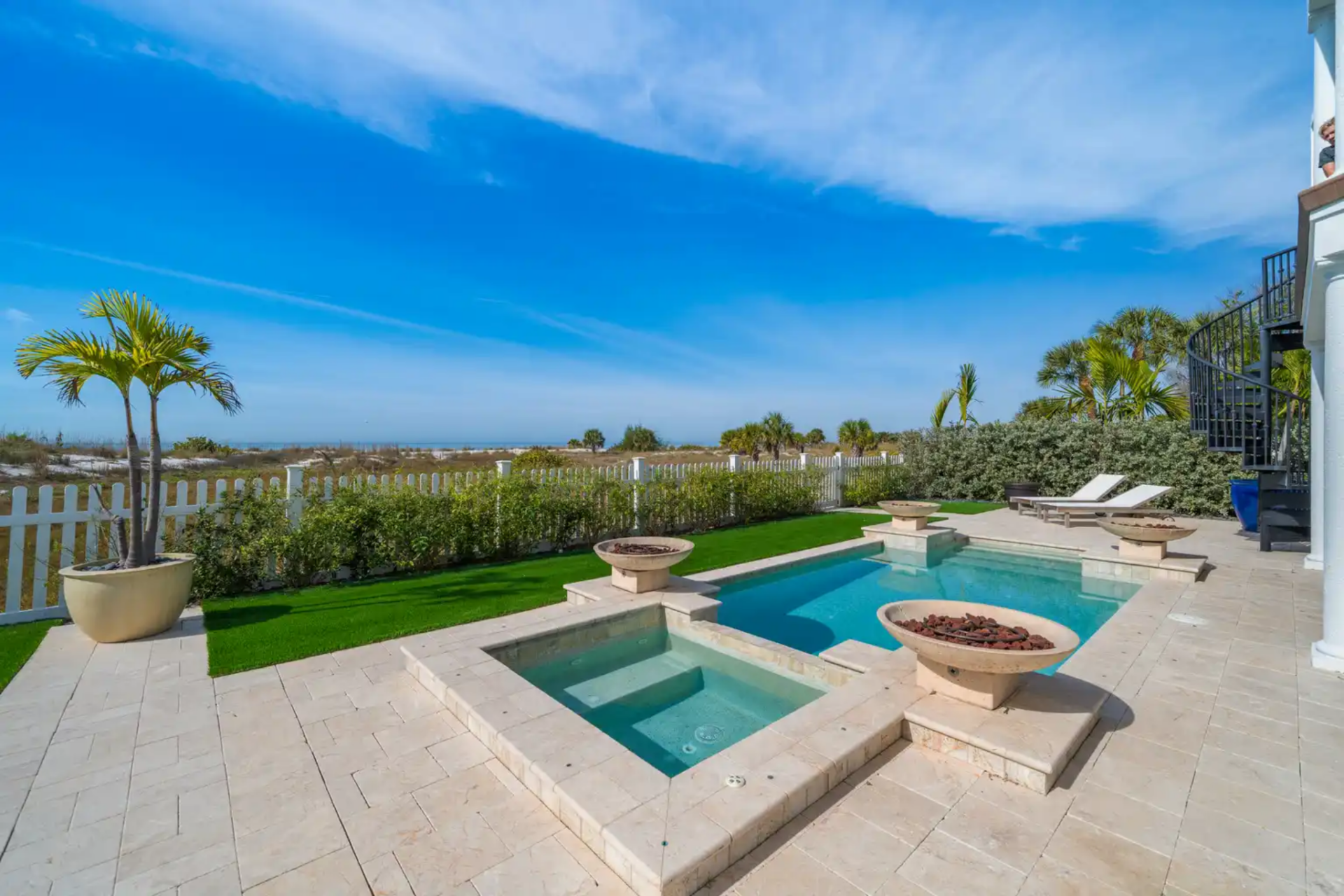 The heated pool and spa sit directly in view, framed by stone decking, integrated fire bowls, and clean sightlines that keep the focus on the water and horizon beyond.