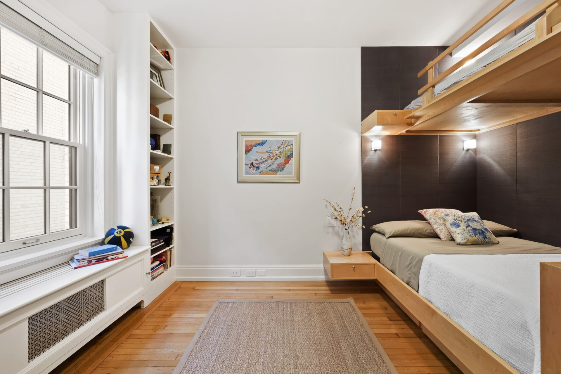 In contrast, the second bedroom has a more contemporary design, defined by clean lines and a custom wood bunk bed with integrated nightstands. 