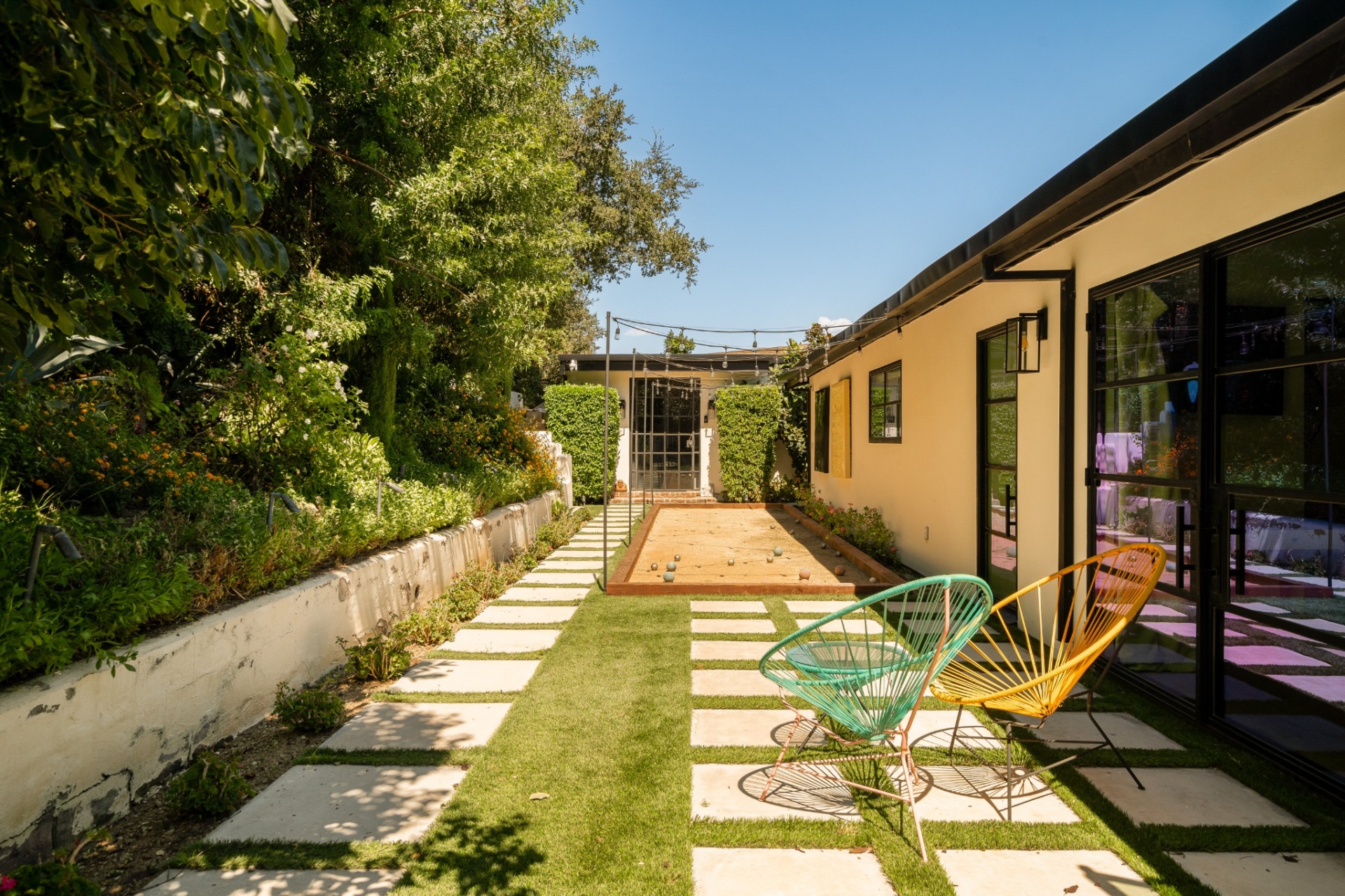 Set along a narrow garden corridor, the private bocce ball court is defined by clean rectangular borders, compact gravel surfacing, and a straight, linear layout that runs parallel to the house. 