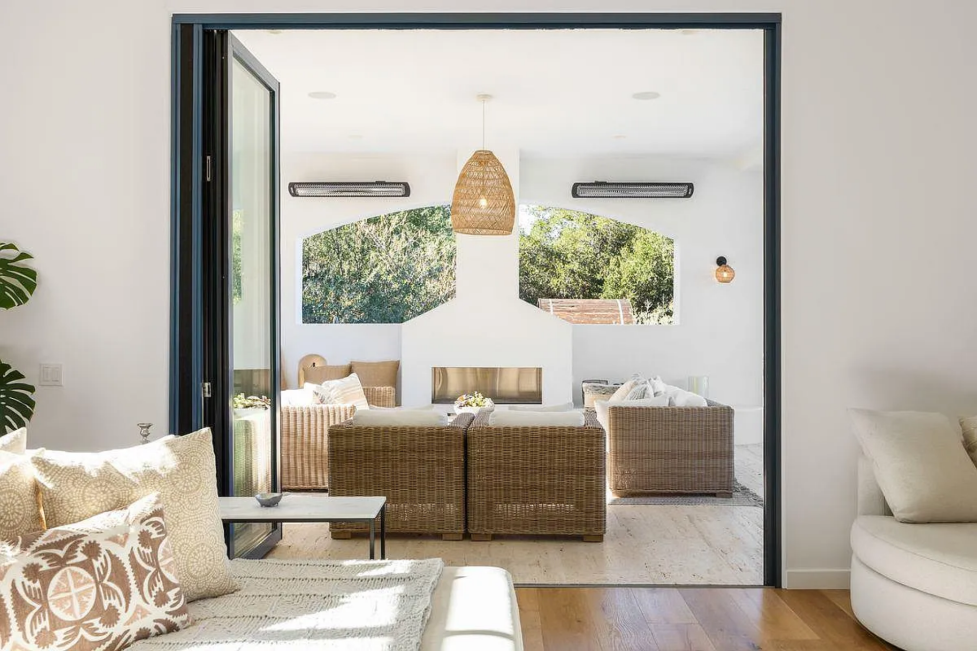 Wicker seating clusters around a built-in fireplace between an arched opening, echoing the home’s Mexican-influenced design details.