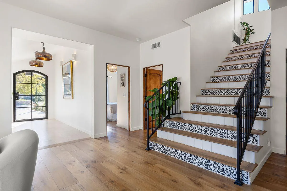 Further inside, patterned tile risers along the staircase are paired with warm wood steps and a black iron railing.
