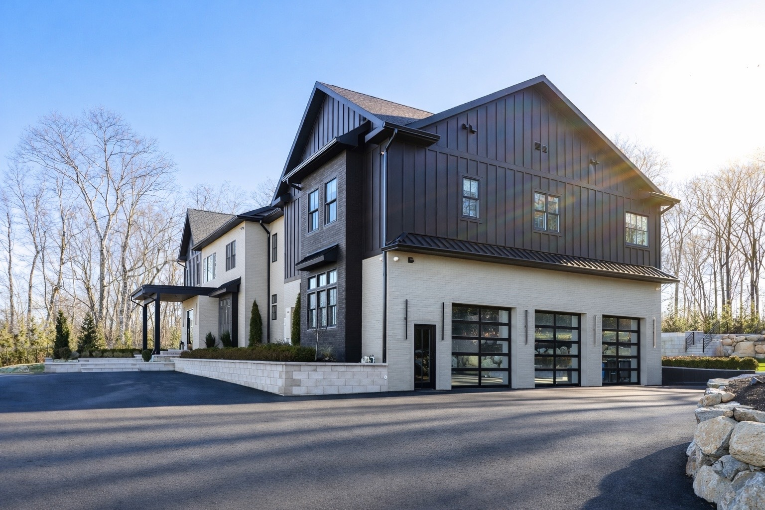The residence rises with sharp black vertical siding contrasted against crisp white brick, giving the exterior a modern, high-impact look.