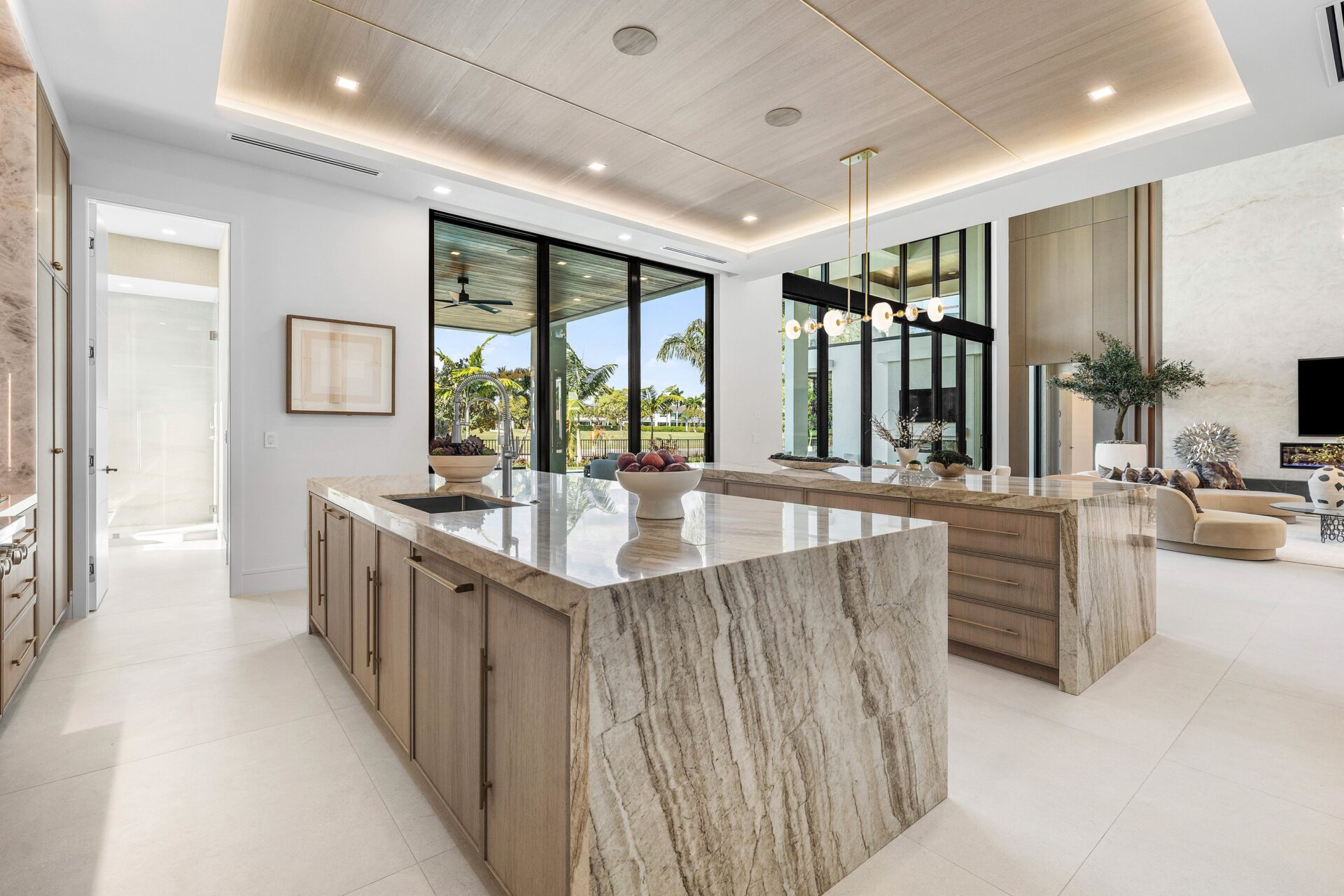 Behind the living area, the chef’s kitchen opens as a bright, oversized workspace centered around two large stone islands.