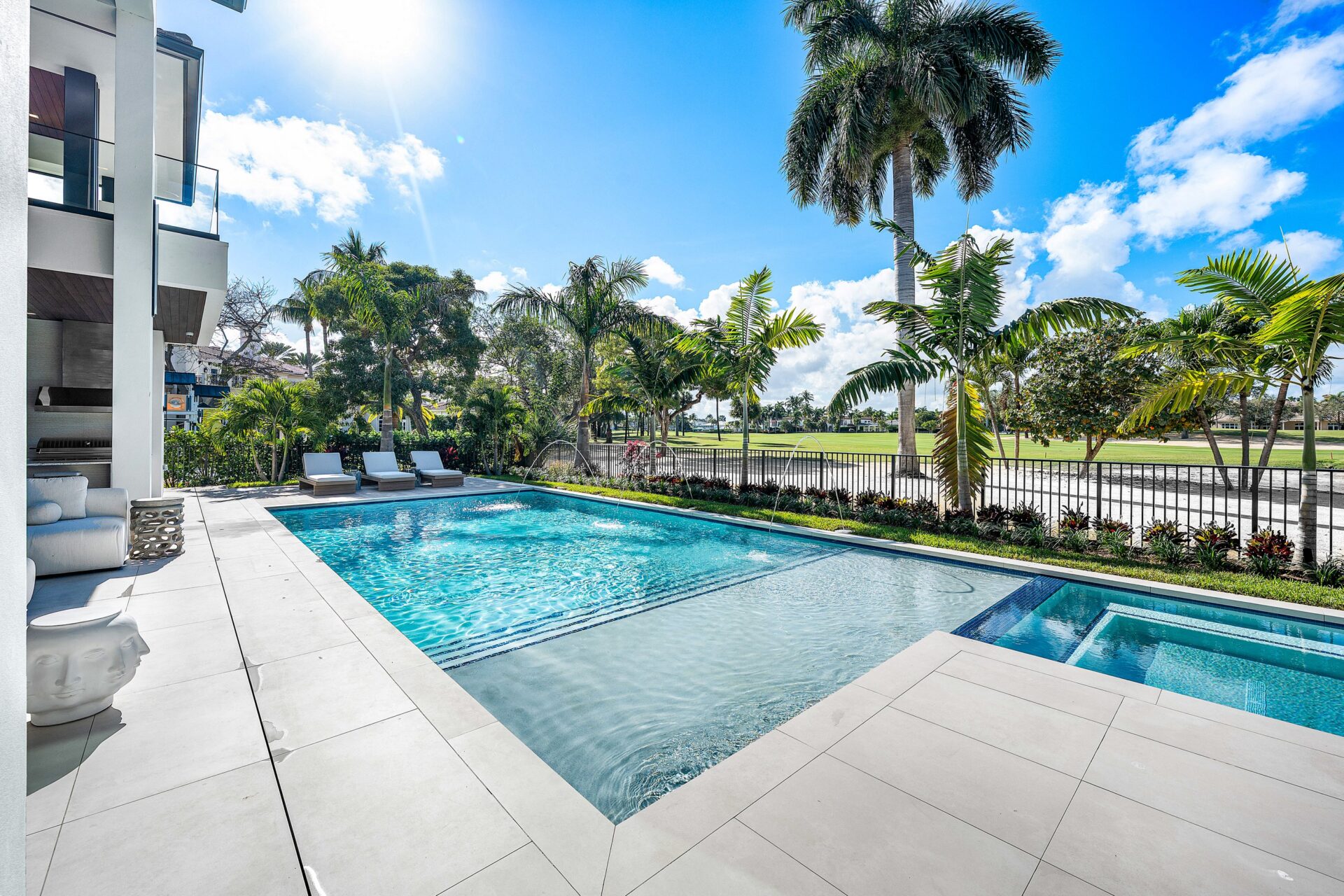 The pool runs parallel to the back of the house with a shallow sun shelf at one end and a raised spa tied into the same clean-lined layout.