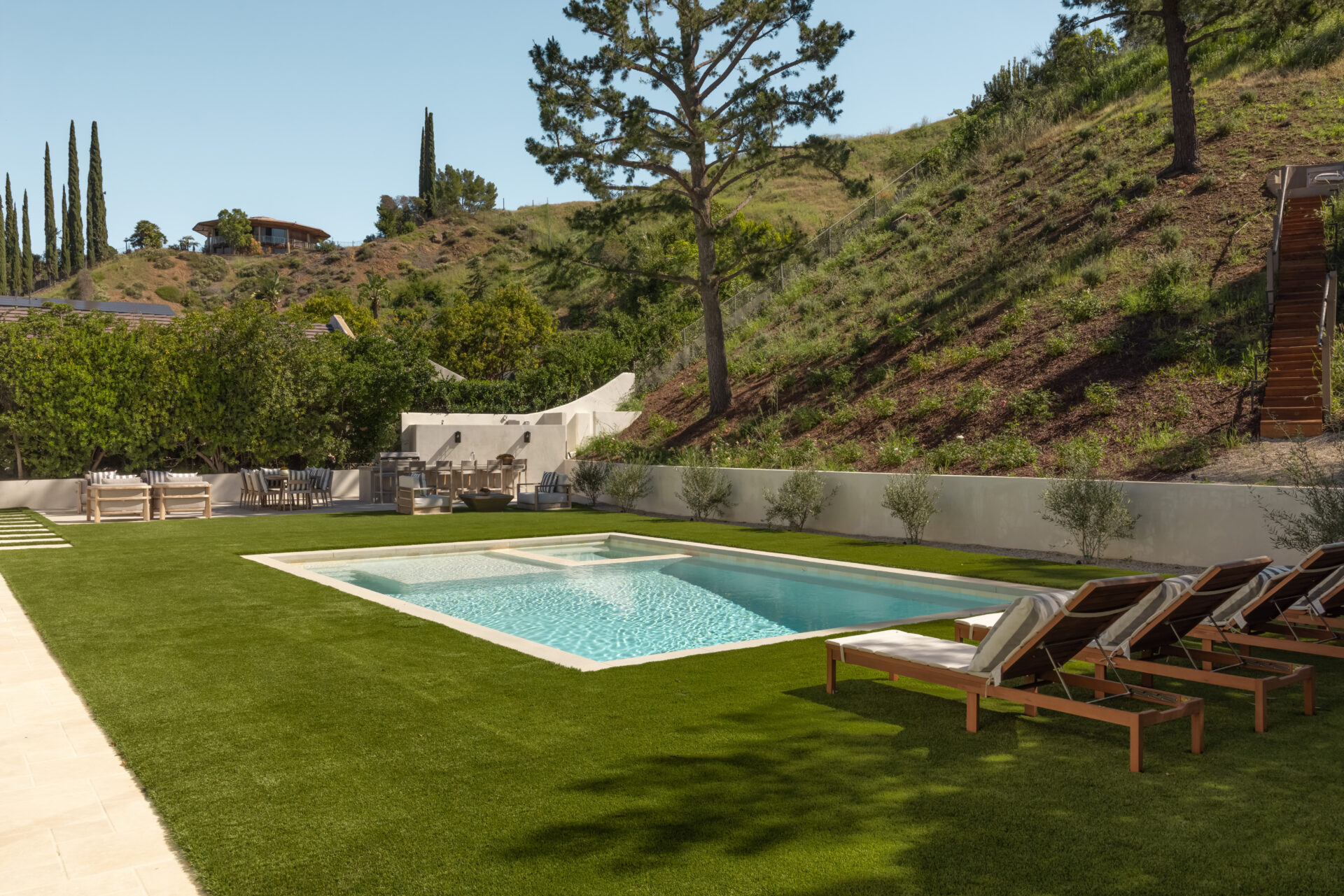Outside, the backyard centers around a rectangular pool and spa set into a wide lawn. 