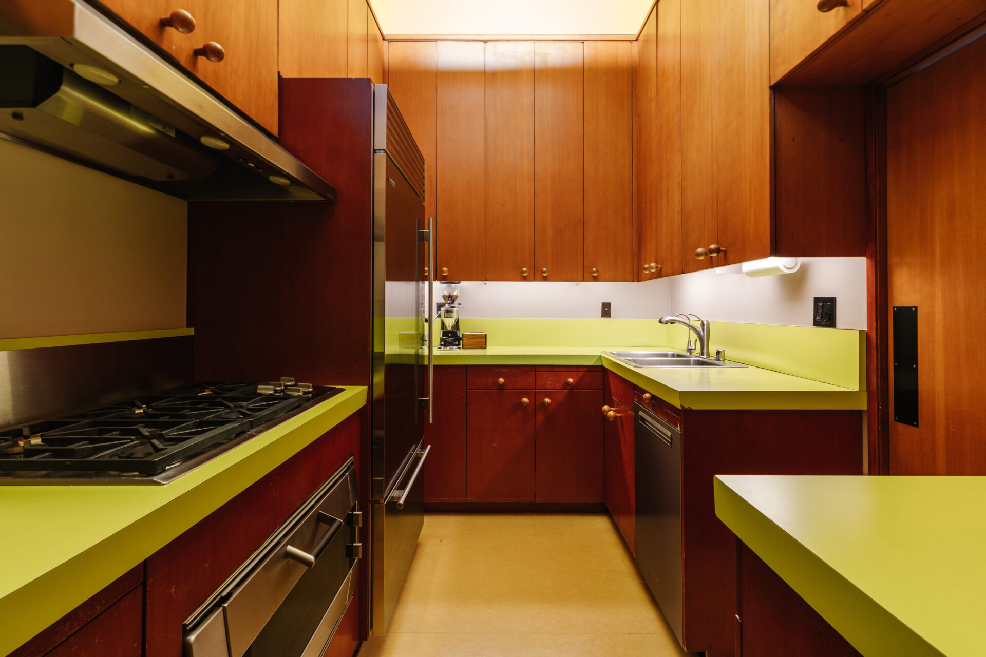 Around the corner, the kitchen features lime green countertops that pop vividly against the rich brown oak cabinets lining the walls.