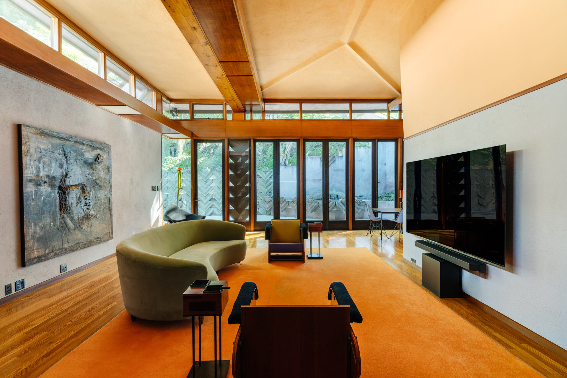 A soaring vaulted ceiling with exposed wood beams stretches overhead, while a wall of glass doors and clerestory windows floods the room with natural light.