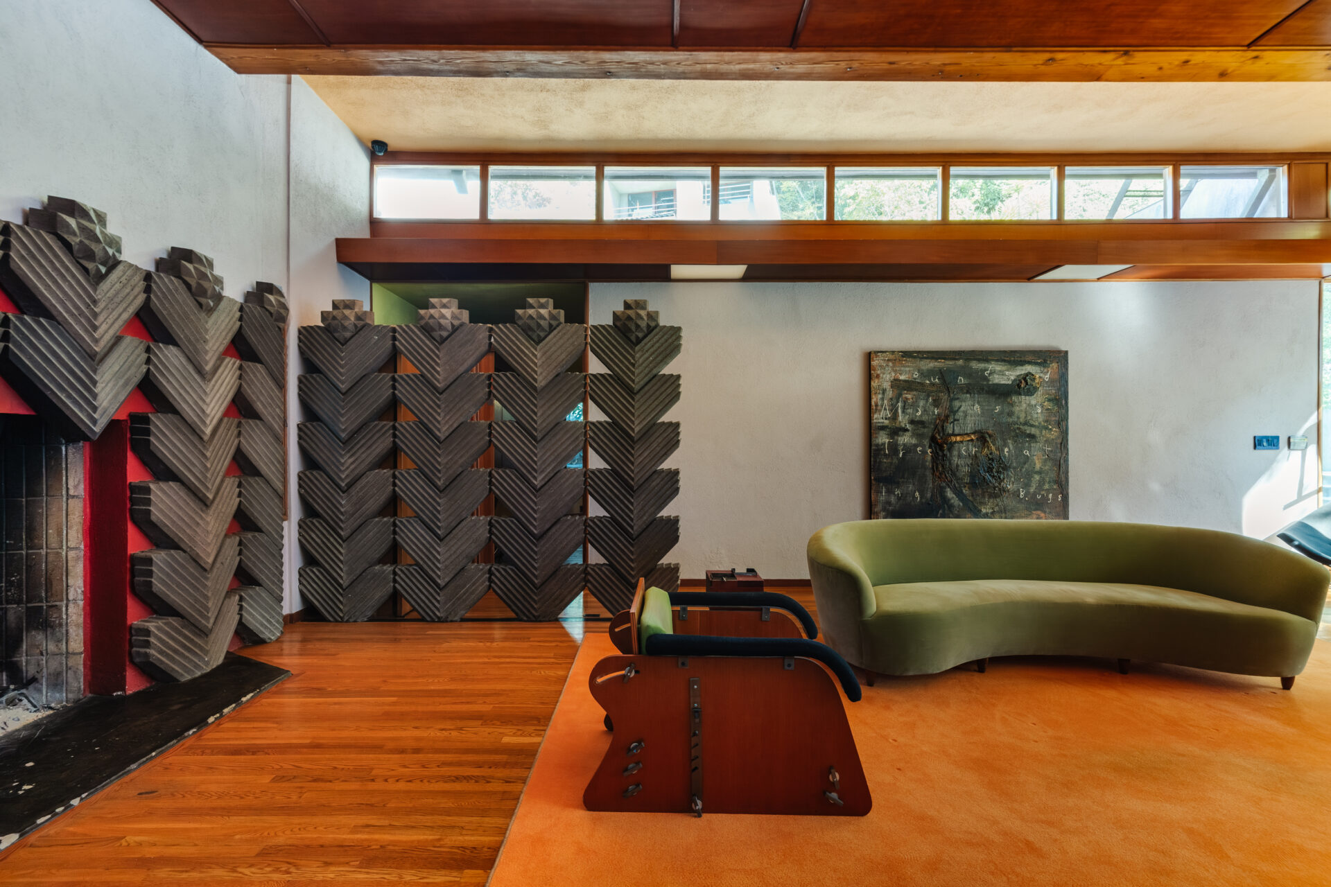 At the far end of the room, the home’s distinctive geometric tile fireplace acts as a visual centerpiece. 