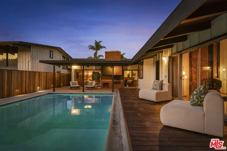 Vertical pool stretches along the side on a one-story house towards a covered patio.