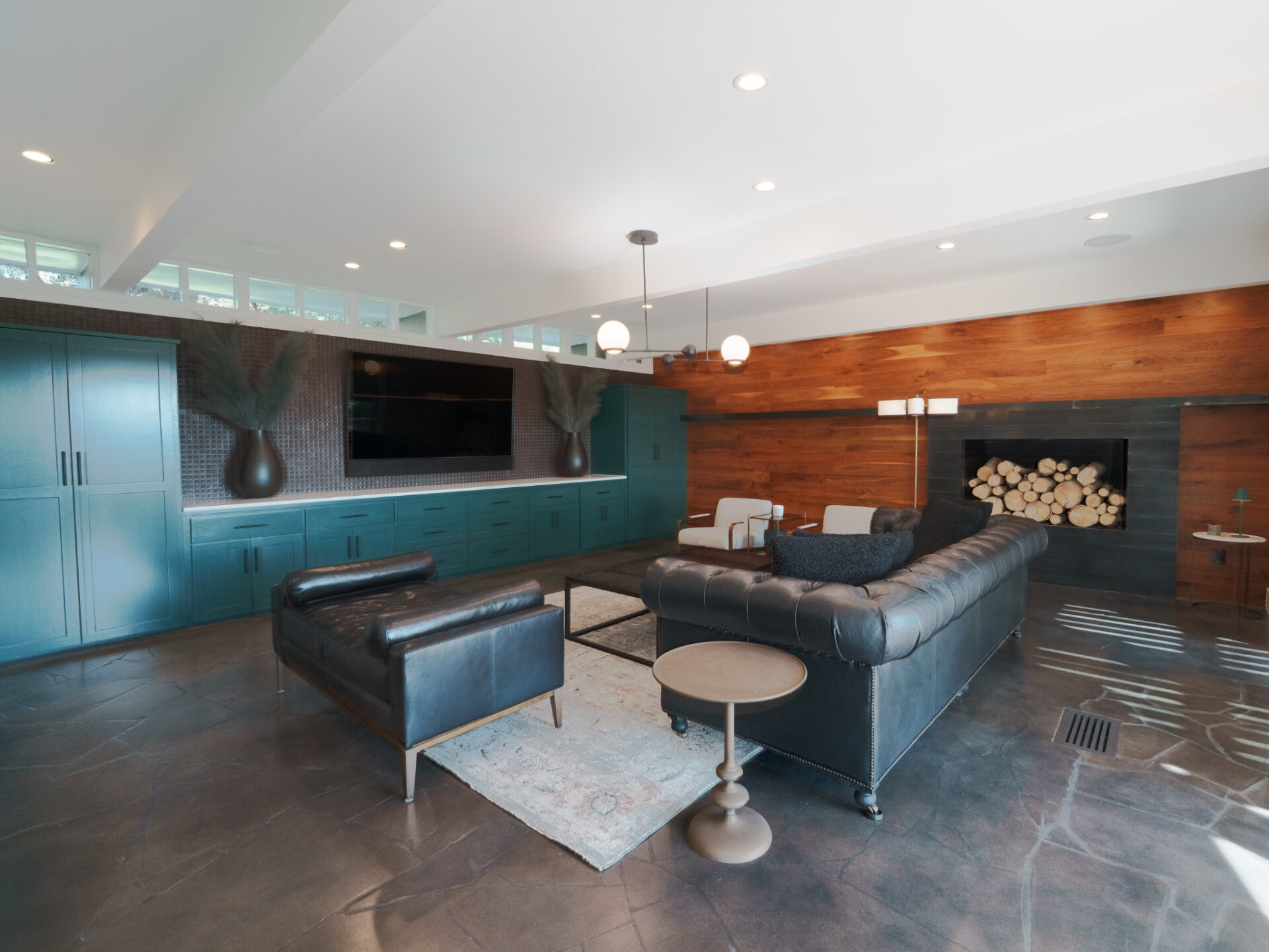 Along one wall, custom teal built-ins run nearly the full length of the room and another features a horizontal wood-paneled accent wall wraps around a fireplace.